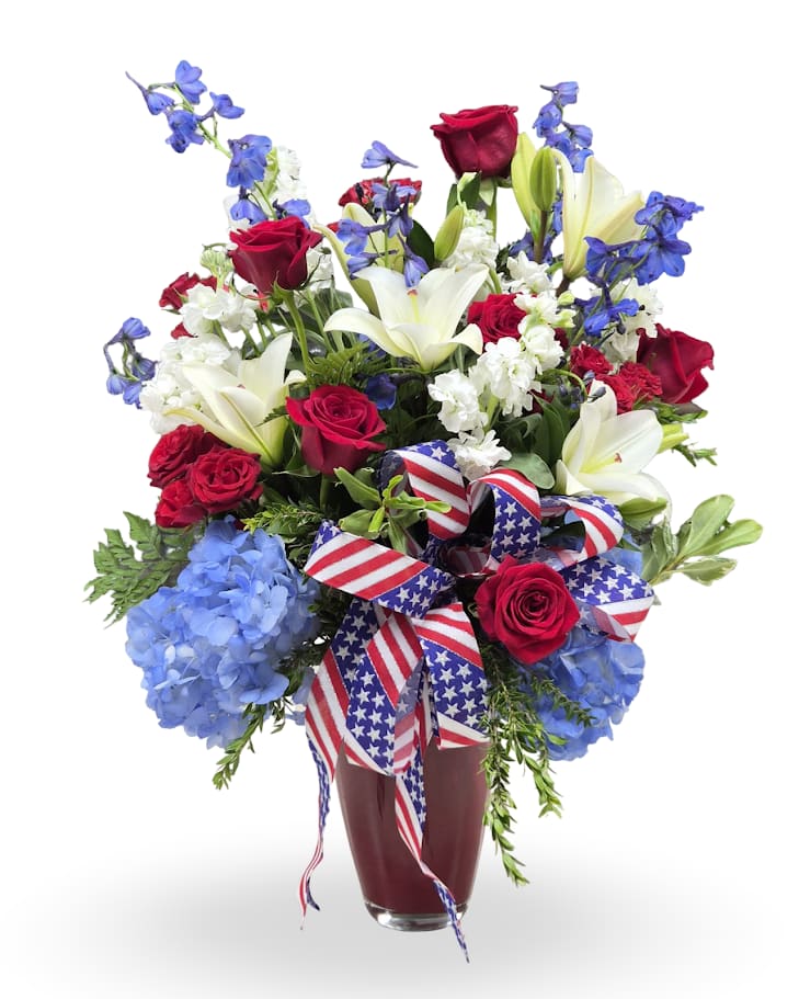 Stars &amp; Stripes  - A bold red, white, and blue arrangement made for Fourth of July or any patriotic celebration - the kind of bouquet that makes the person you're thinking of feel honored and celebrated. Bright reds, crisp whites, and deep blues are arranged upright in a clear glass vase with a festive red, white, and blue ribbon, creating a full, cheerful display perfect for holidays or congratulations.  This compact design features varied heights and a dense, celebratory feel that works well on a mantel, entry table, or as a centerpiece. Arrives ready to display in a red glass vase.