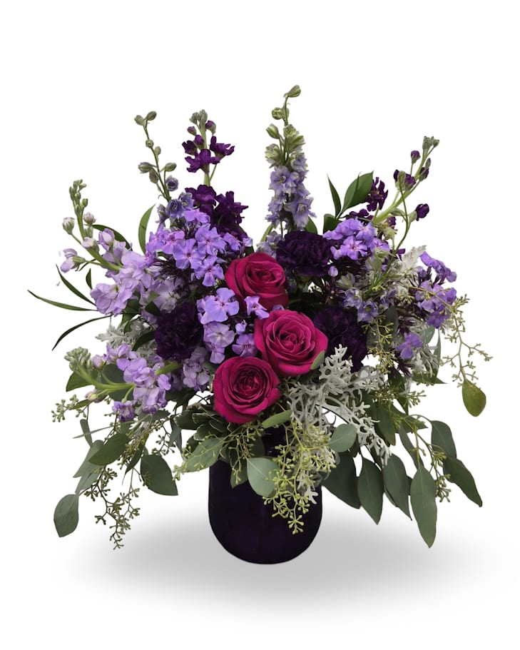 Purple and pink rose arrangement in a dark vase
