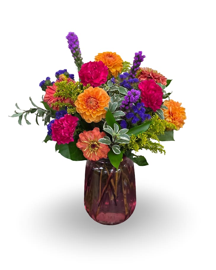 Colorful mixed flower arrangement in a purple glass vase