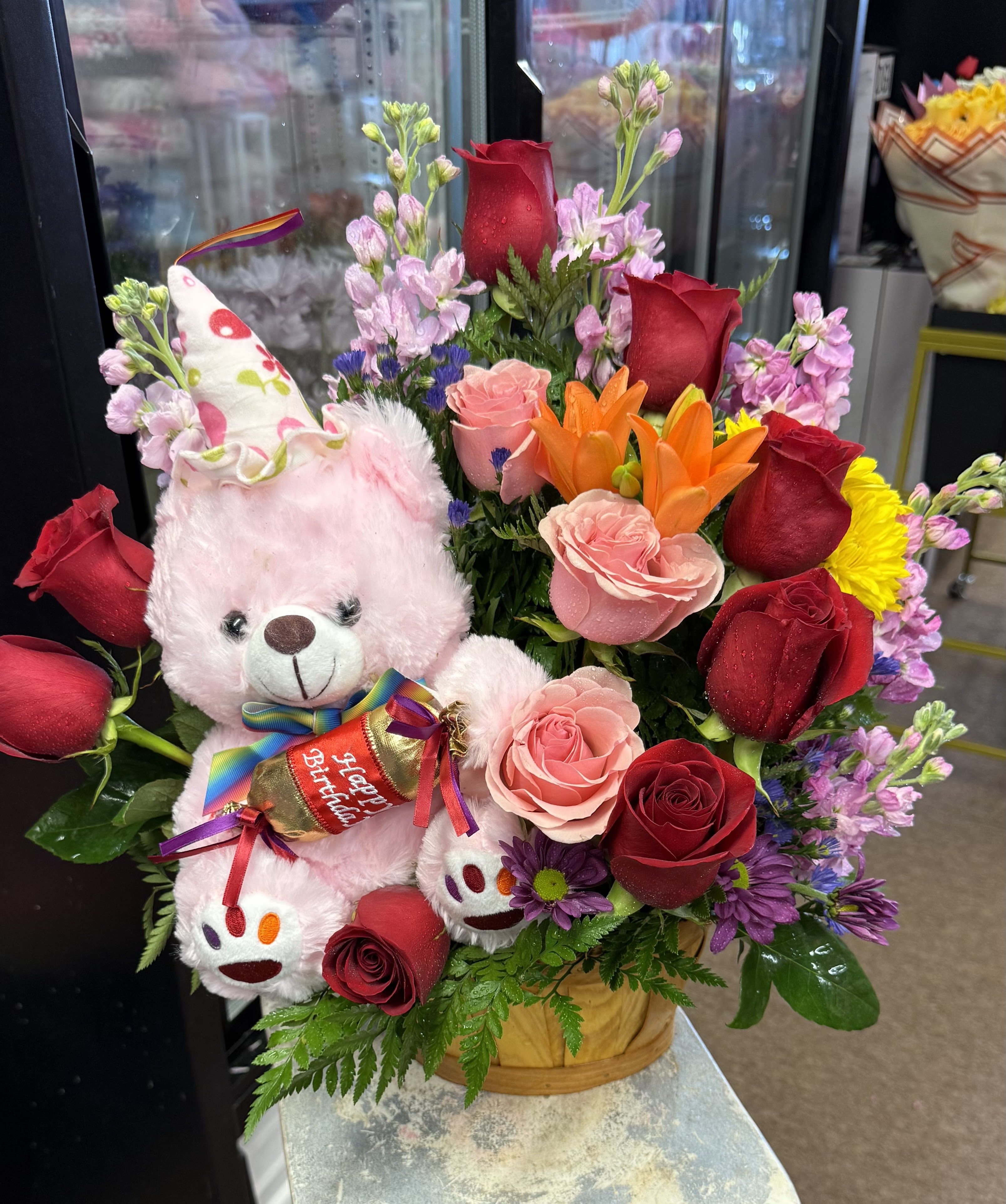 Bouquet with roses, lilies, and a pink teddy bear holding a birthday candy