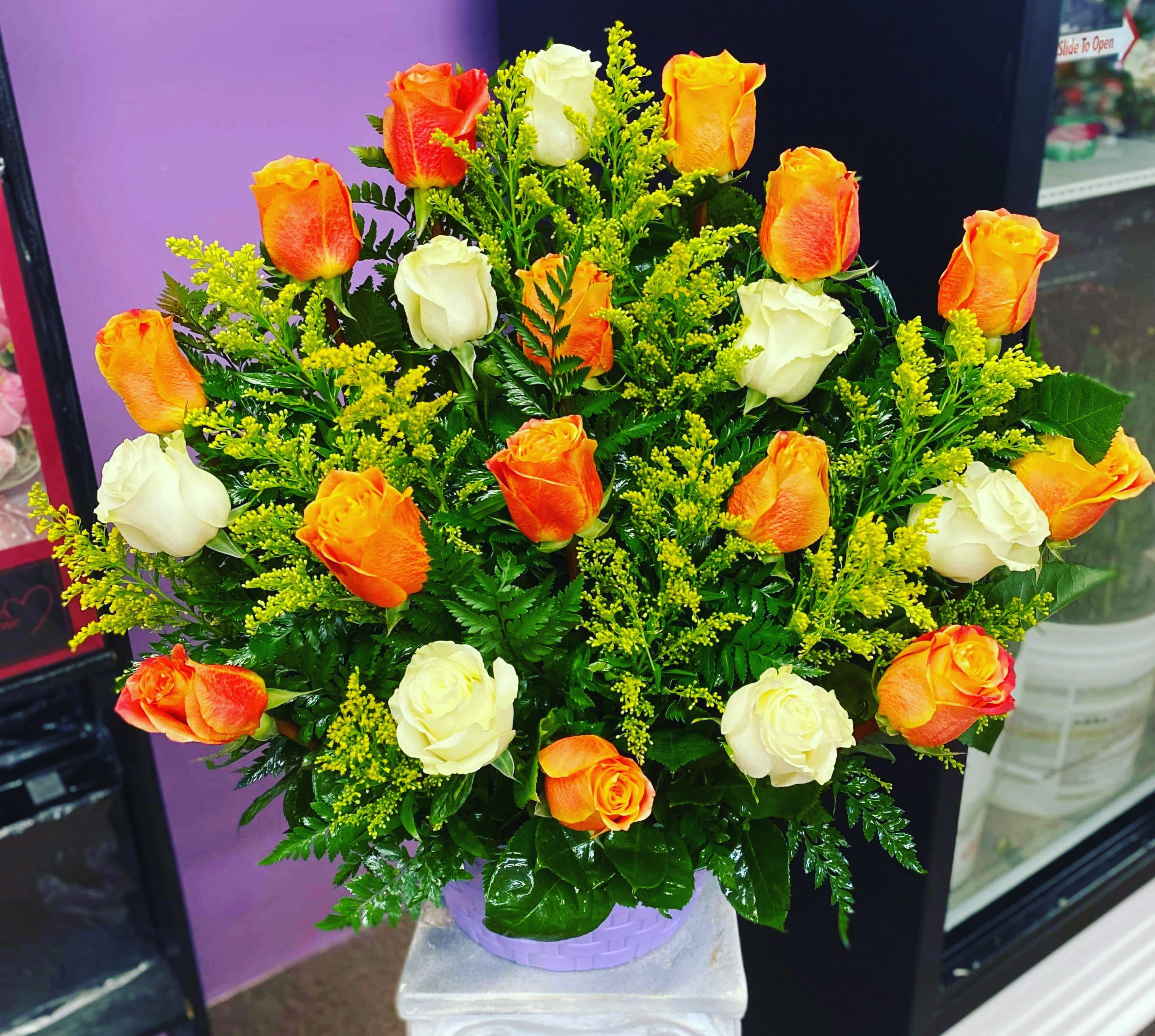 Bouquet of orange and white roses in a lavender container