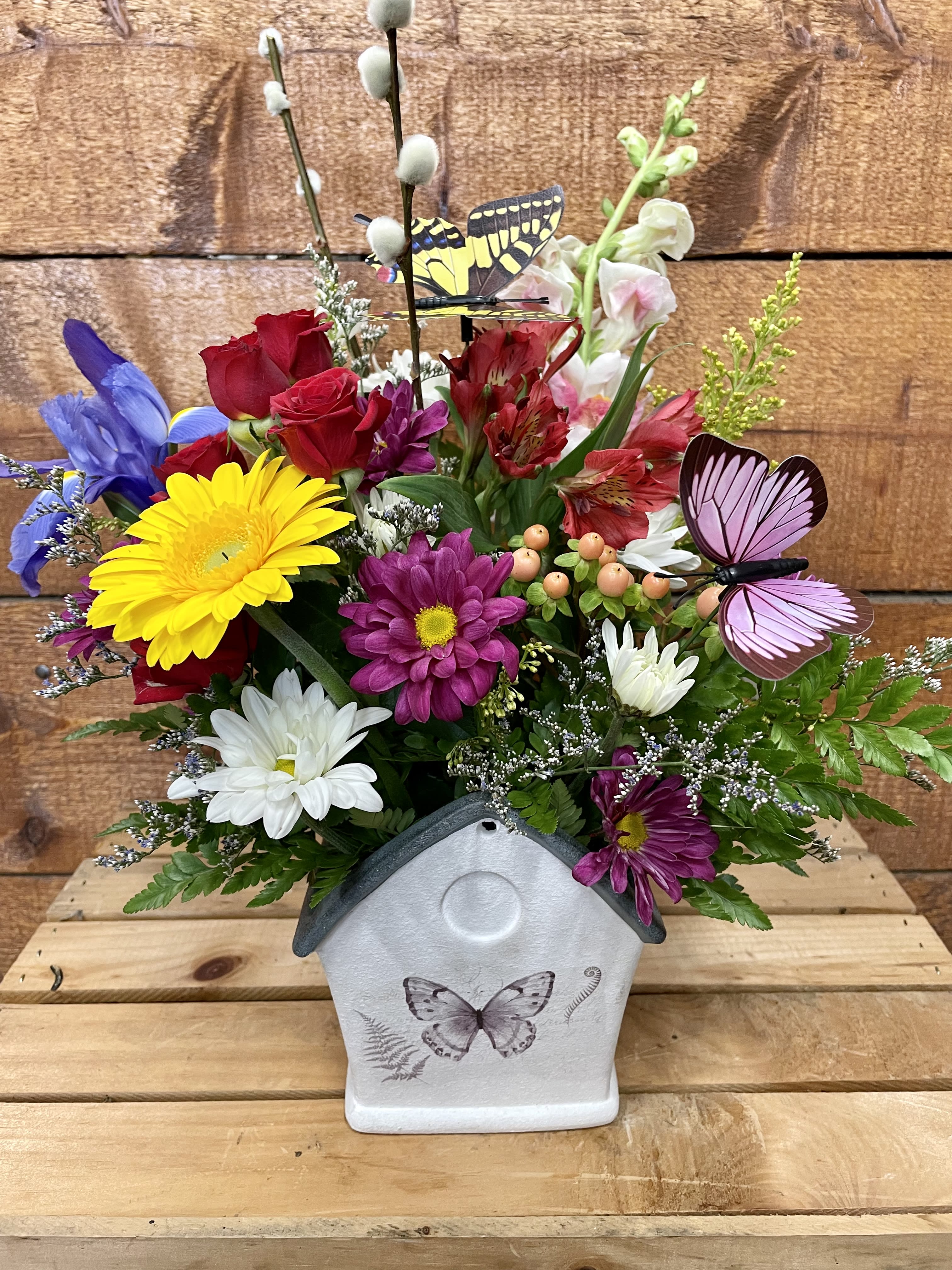 Colorful flower arrangement in a butterfly-decorated house-shaped container
