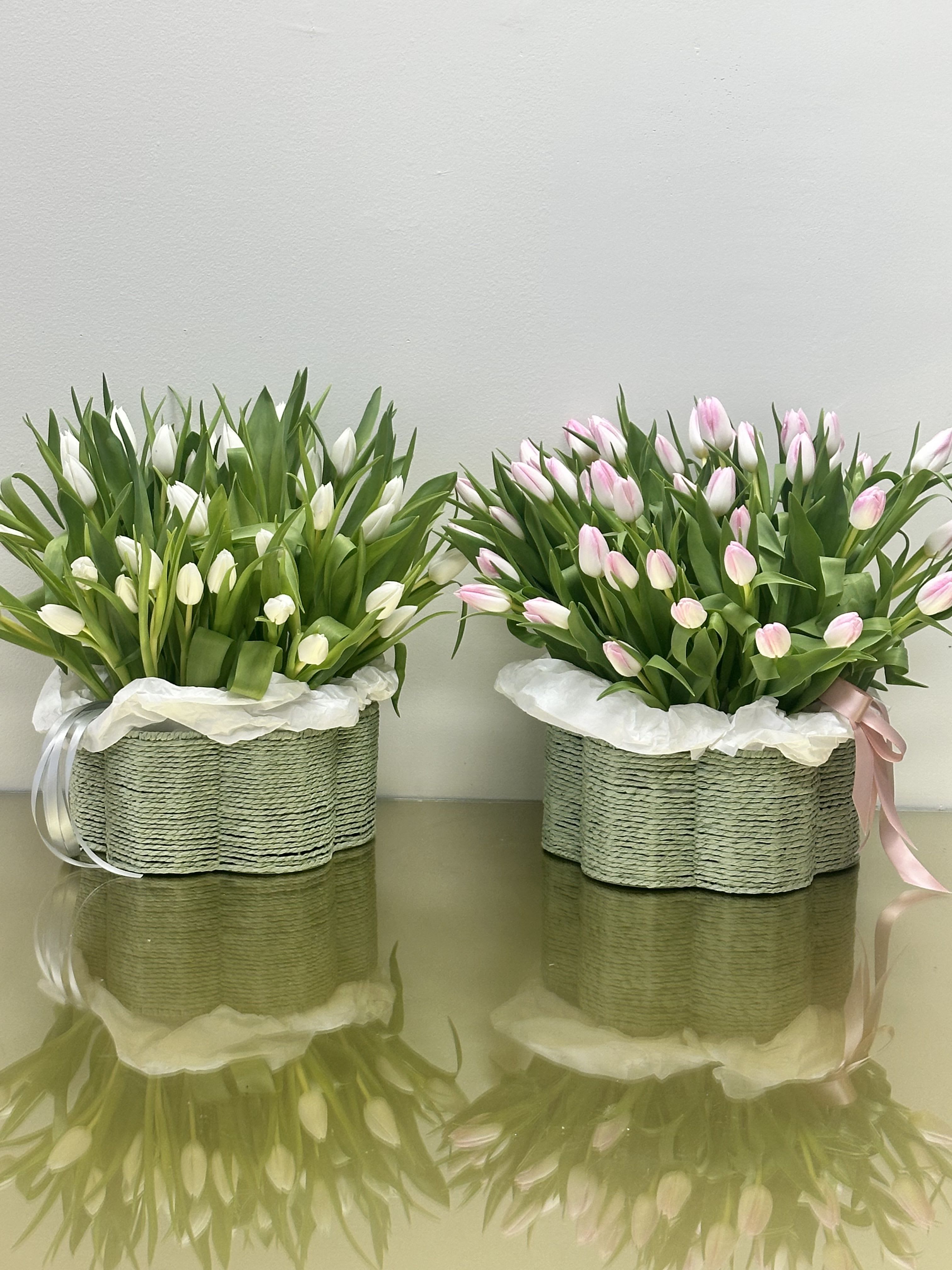 Two tulip arrangements in woven baskets, one white and one pink
