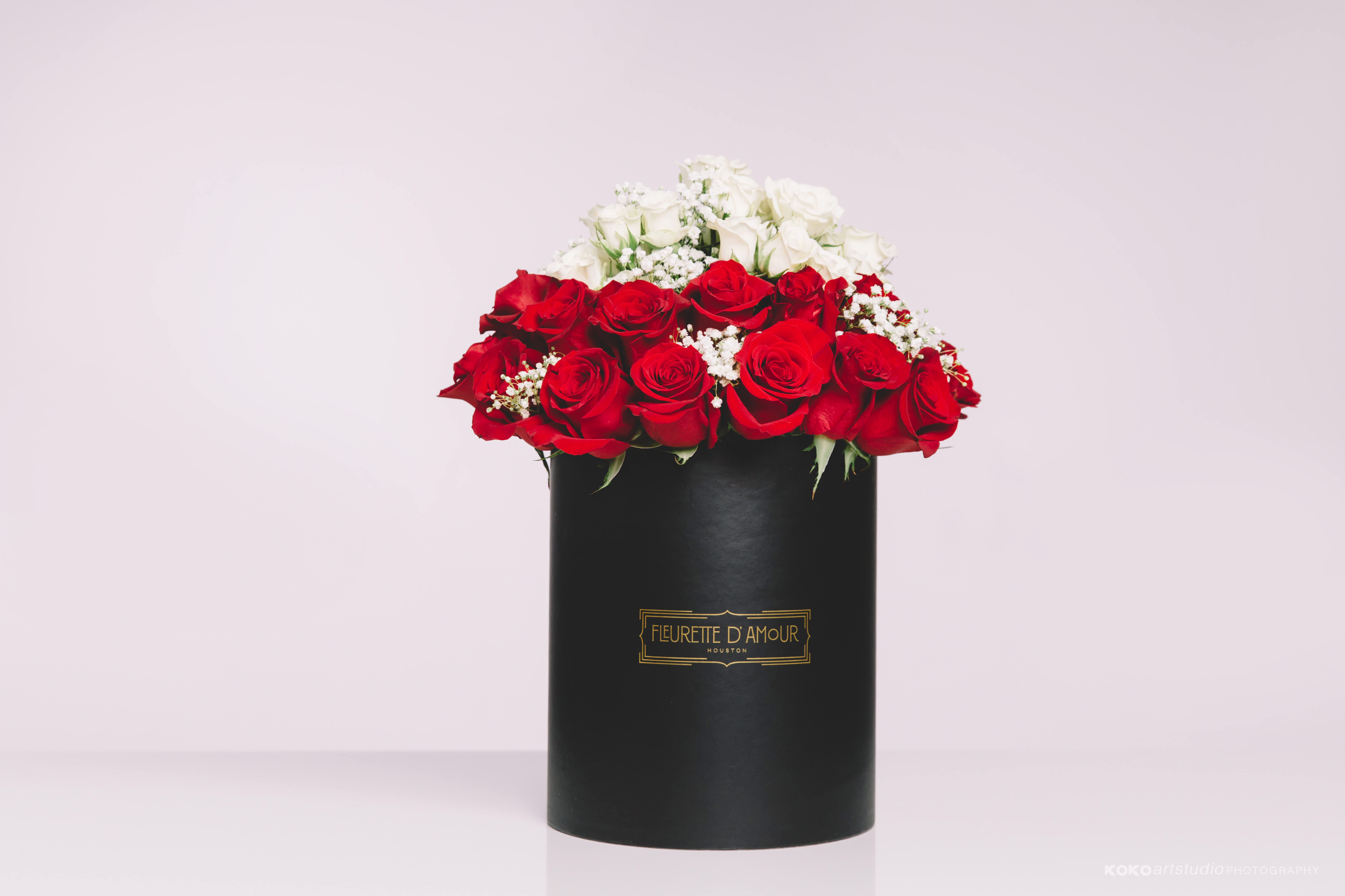 Red and white roses arranged in a black hat box