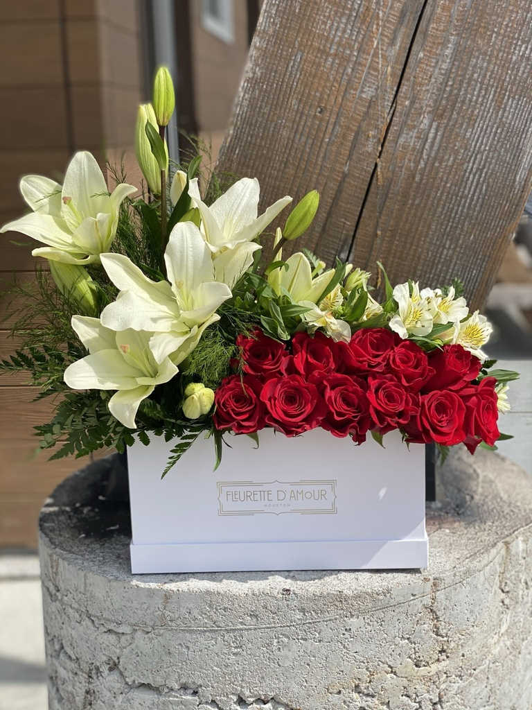 Red roses and white lilies arranged in a white box