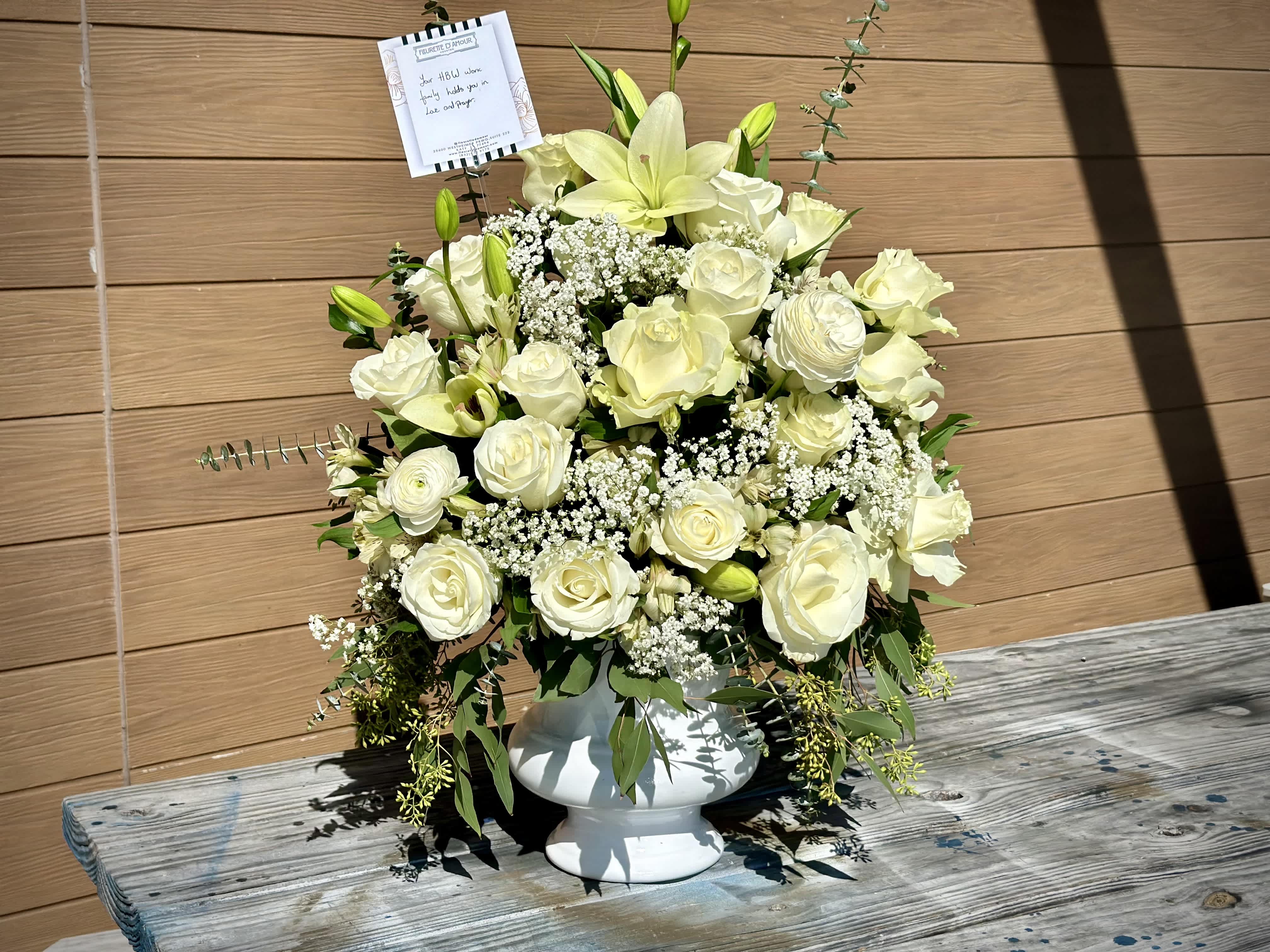 White rose and lily arrangement in a white pedestal vase