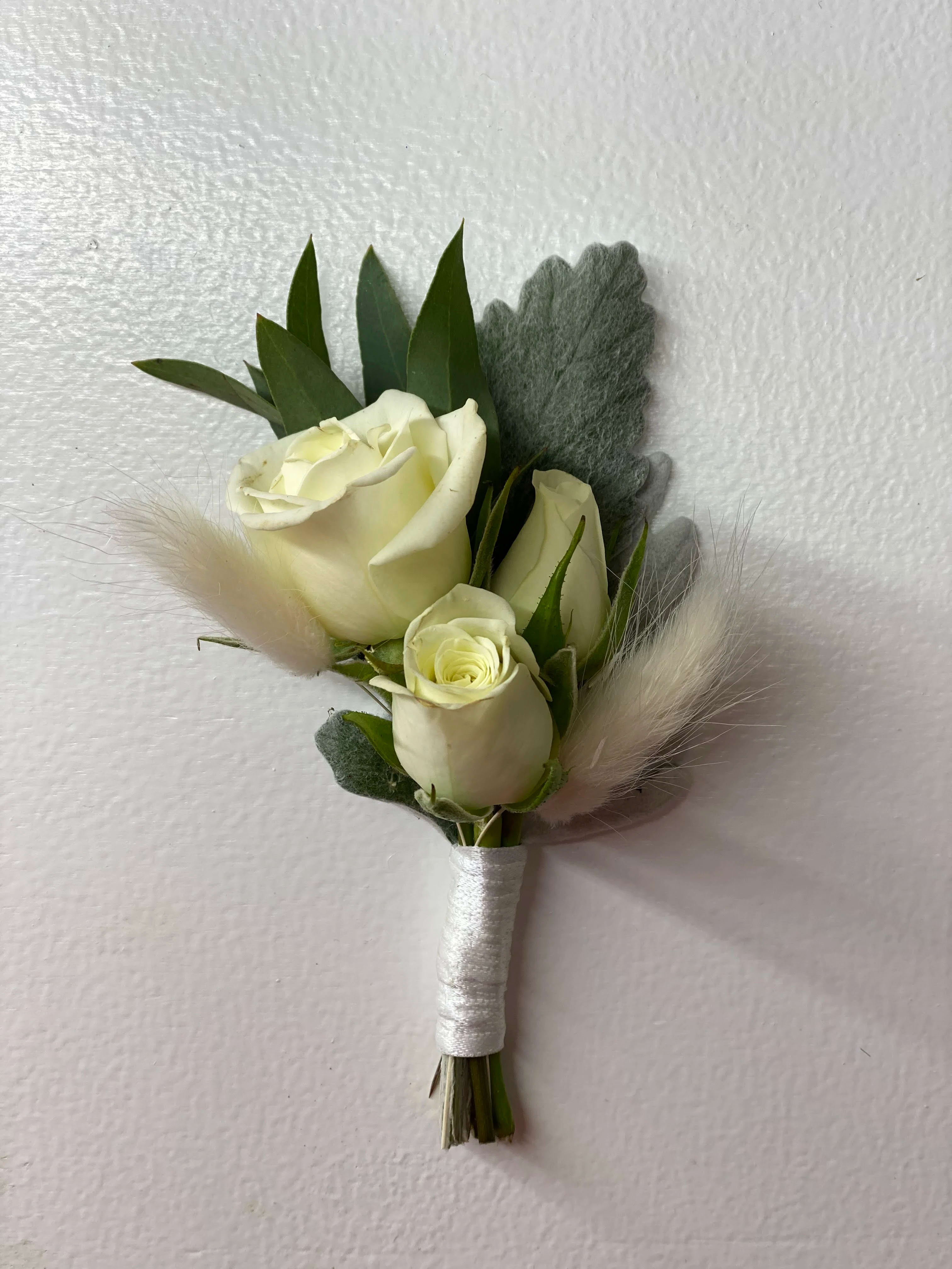 Small white rose boutonniere with gray foliage and soft feather accents