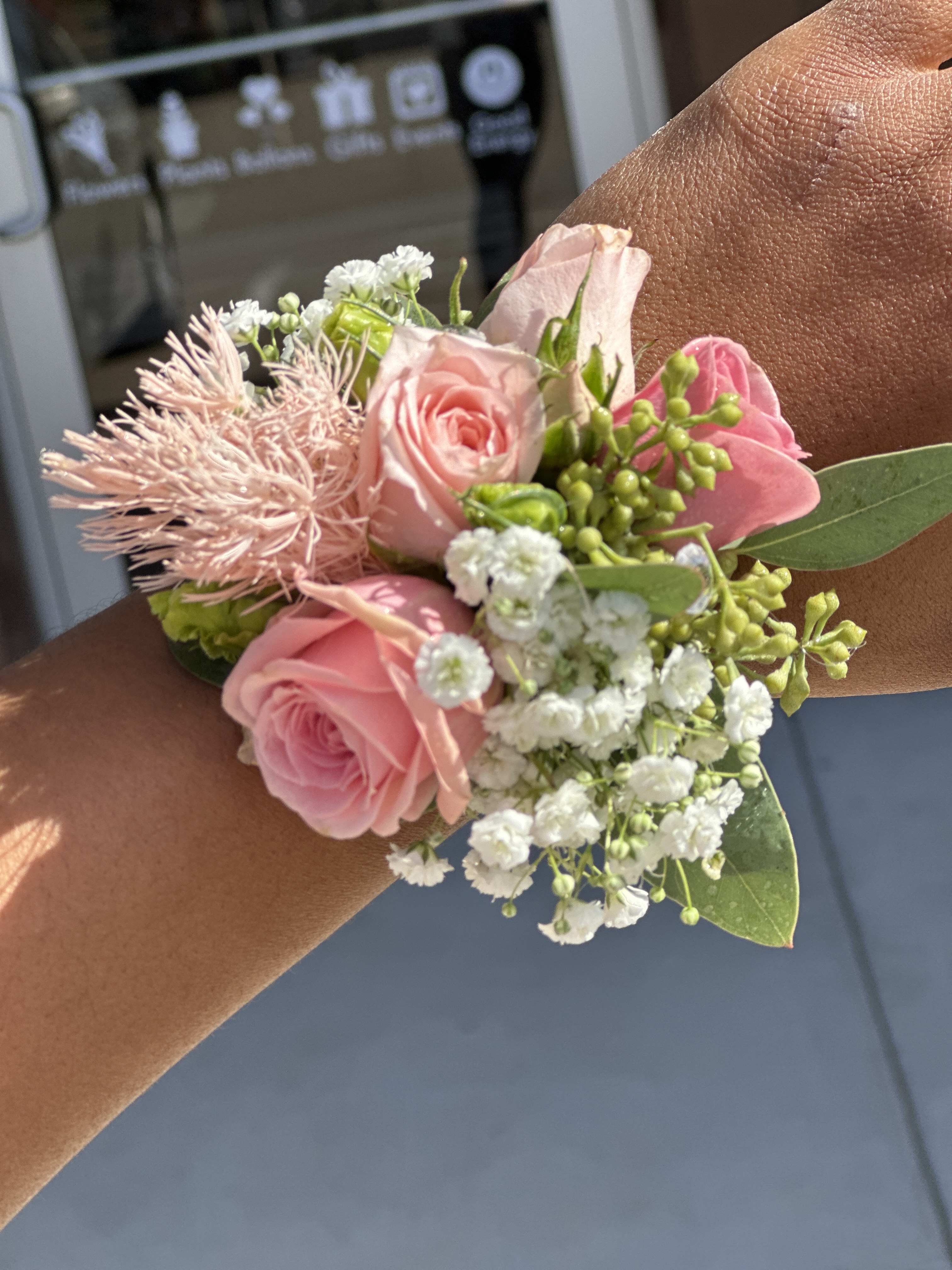 Pink rose wrist corsage with white baby's breath and green accents