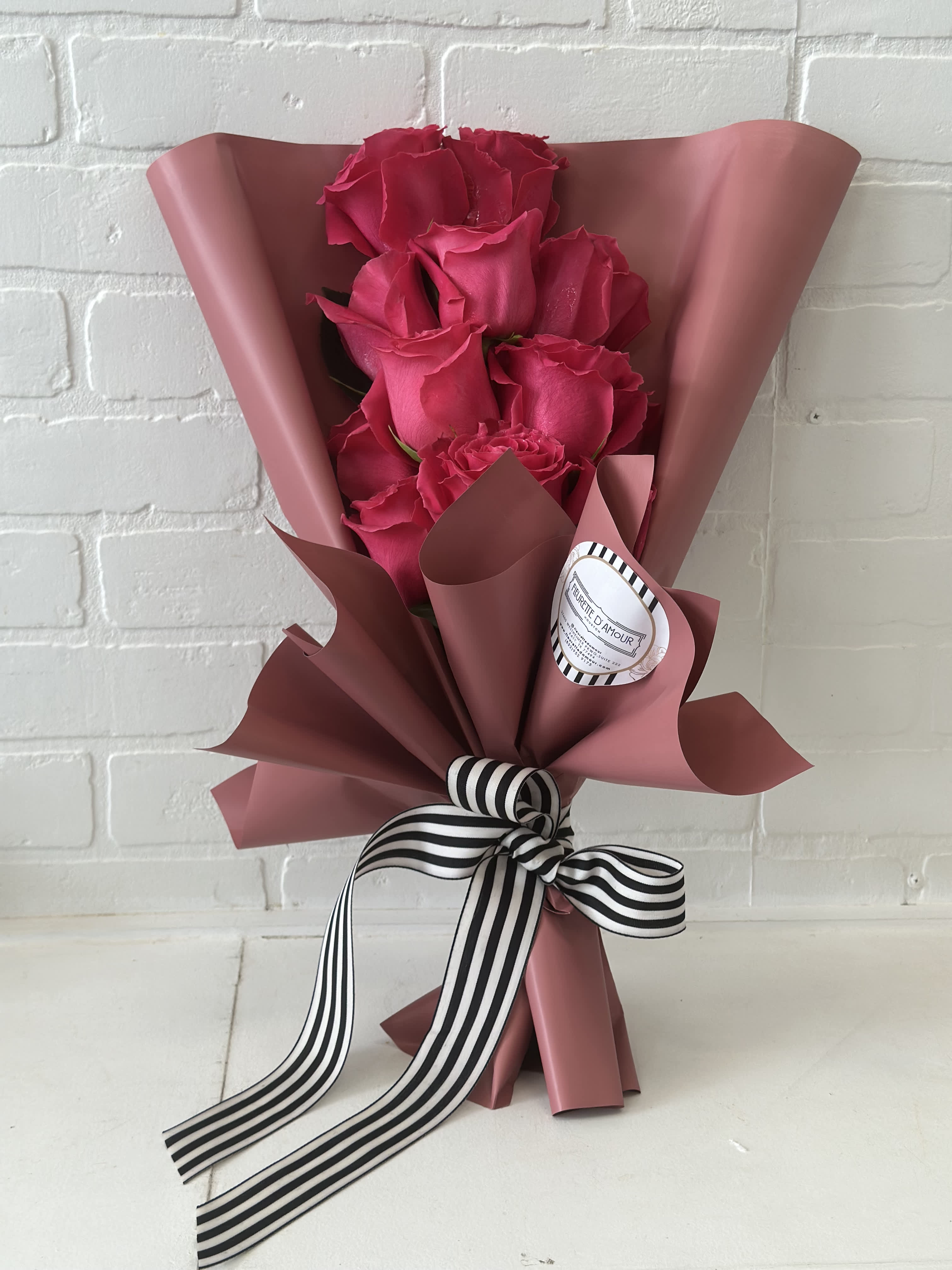 Bouquet of hot pink roses wrapped in dusty pink paper with a striped ribbon