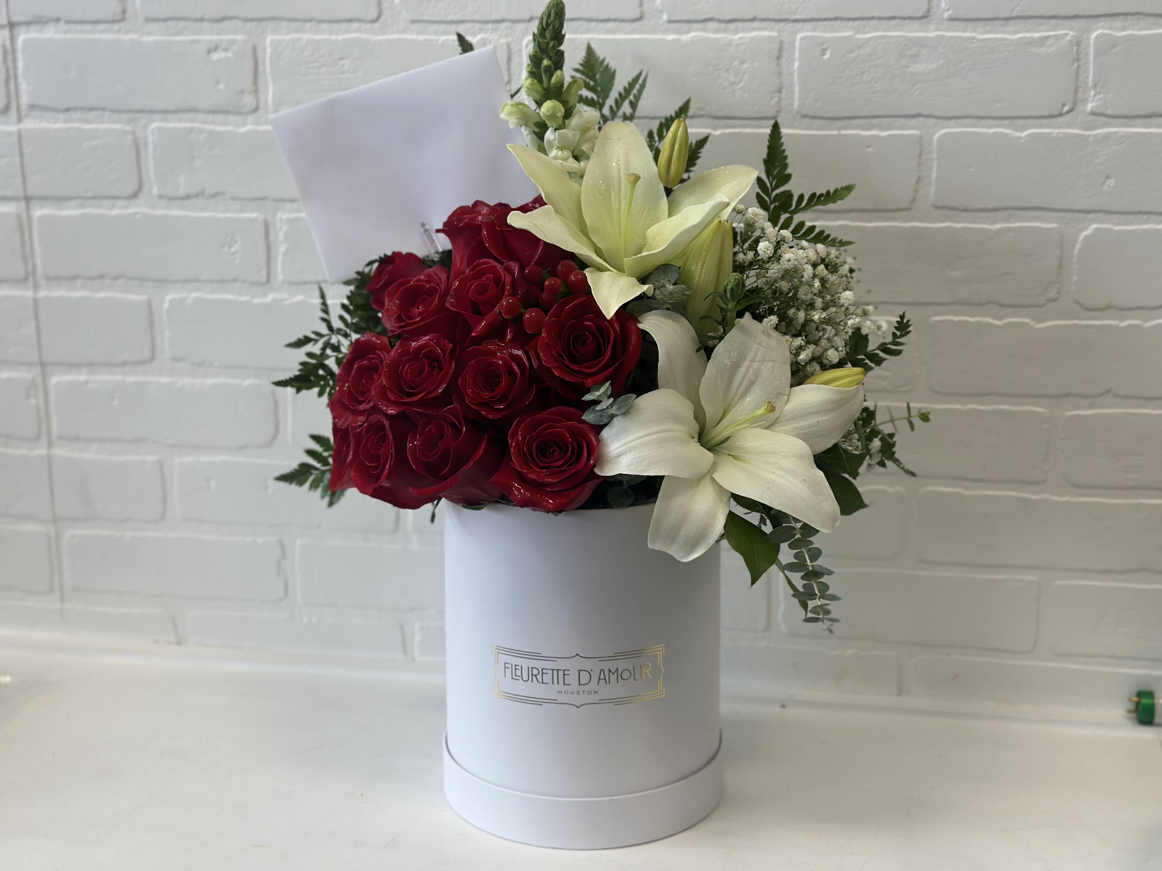 Red roses and white lilies arranged in a white hat box