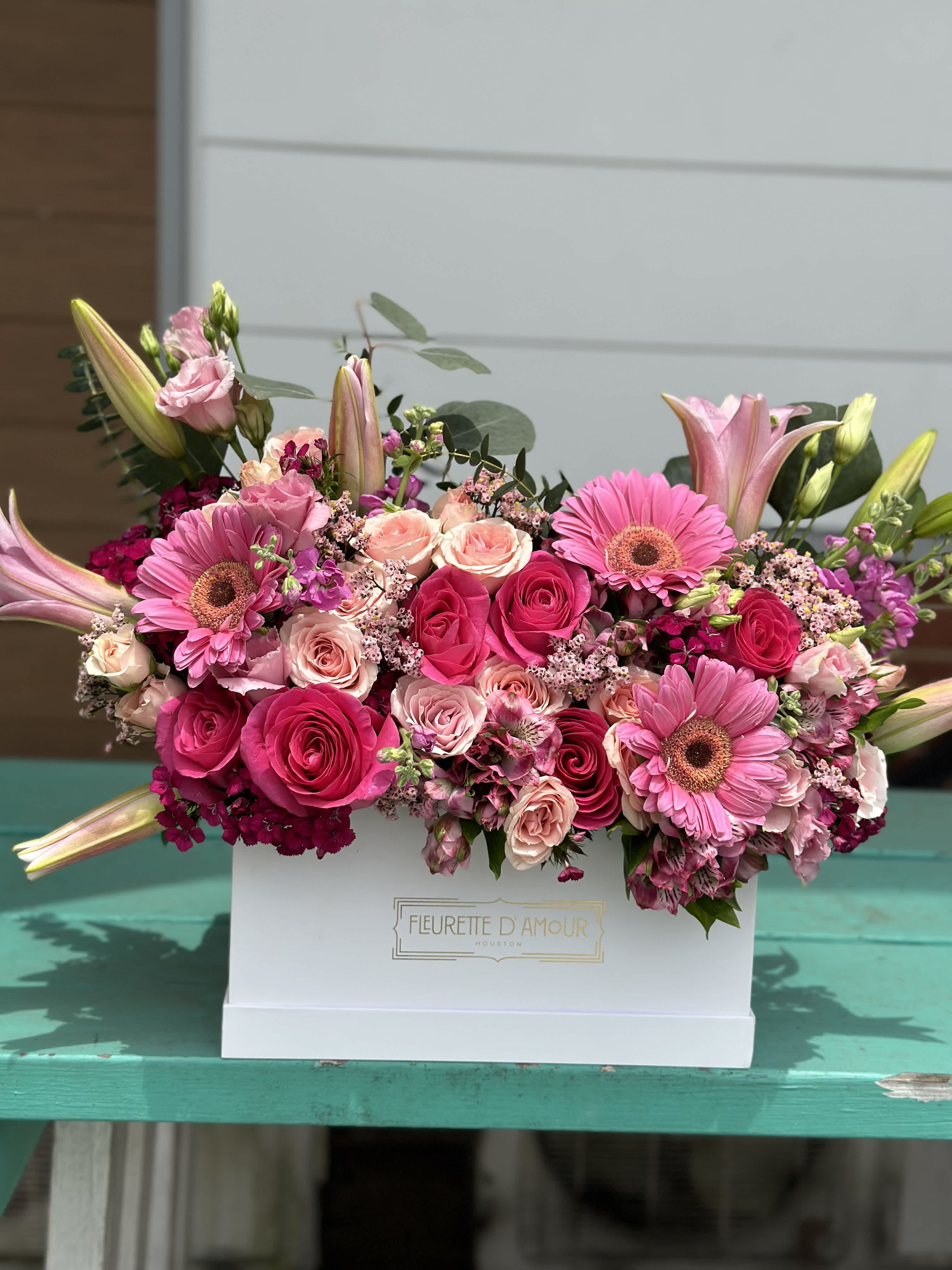 Pink roses and gerbera daisies arranged in a white box