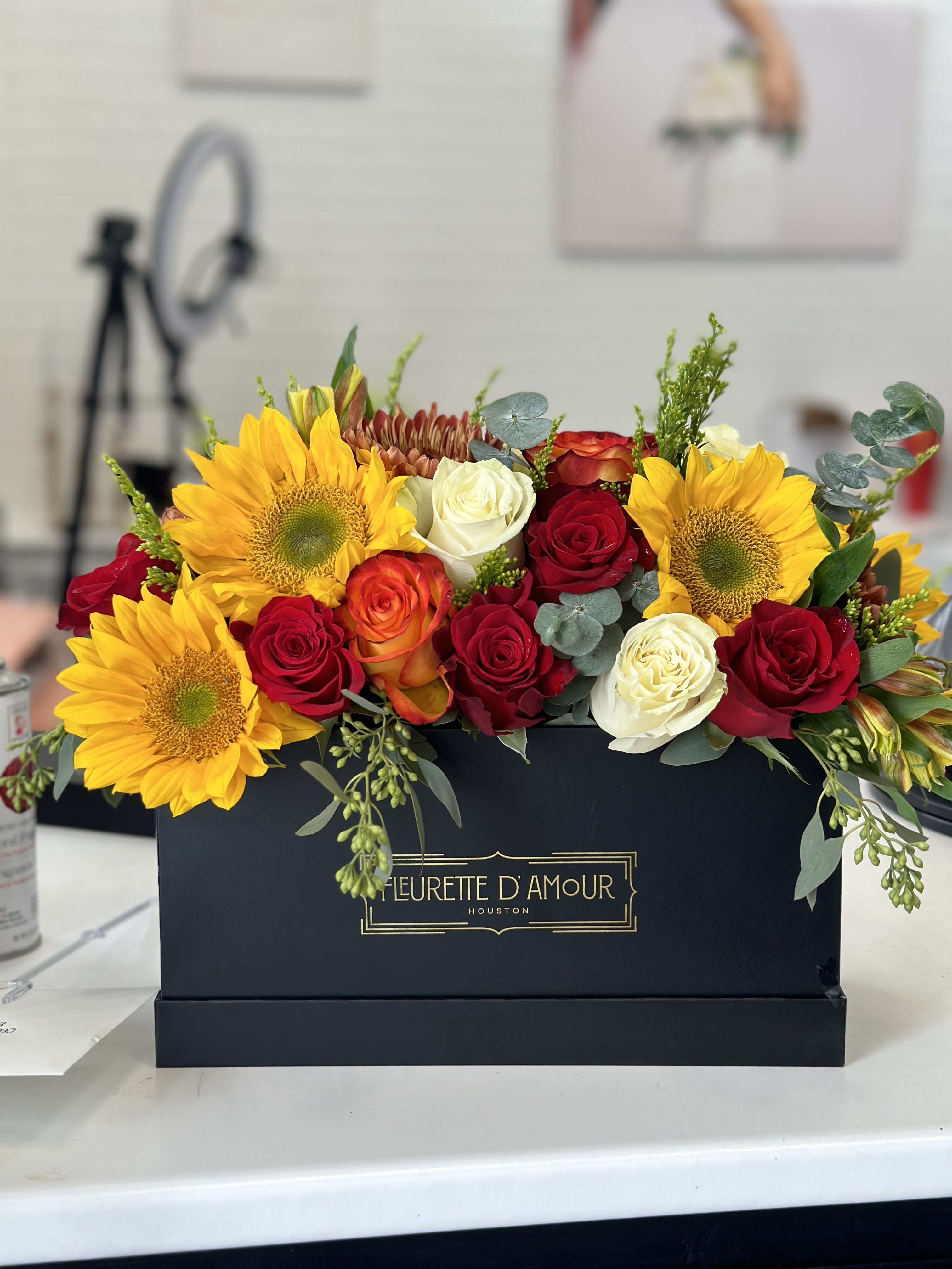 Sunflowers and roses arranged in a black box