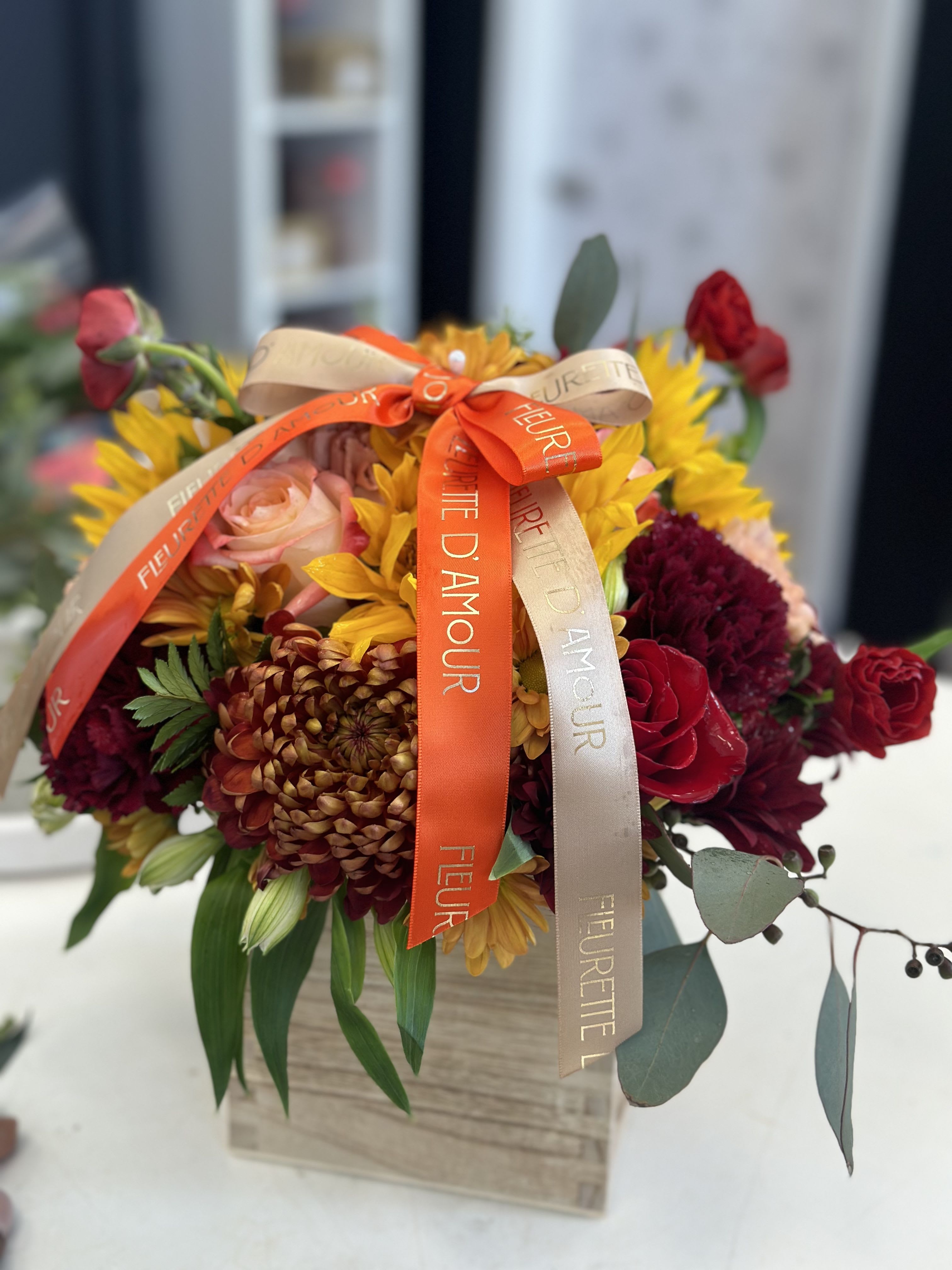 Bouquet of sunflowers, roses, and chrysanthemums with ribbon on a box