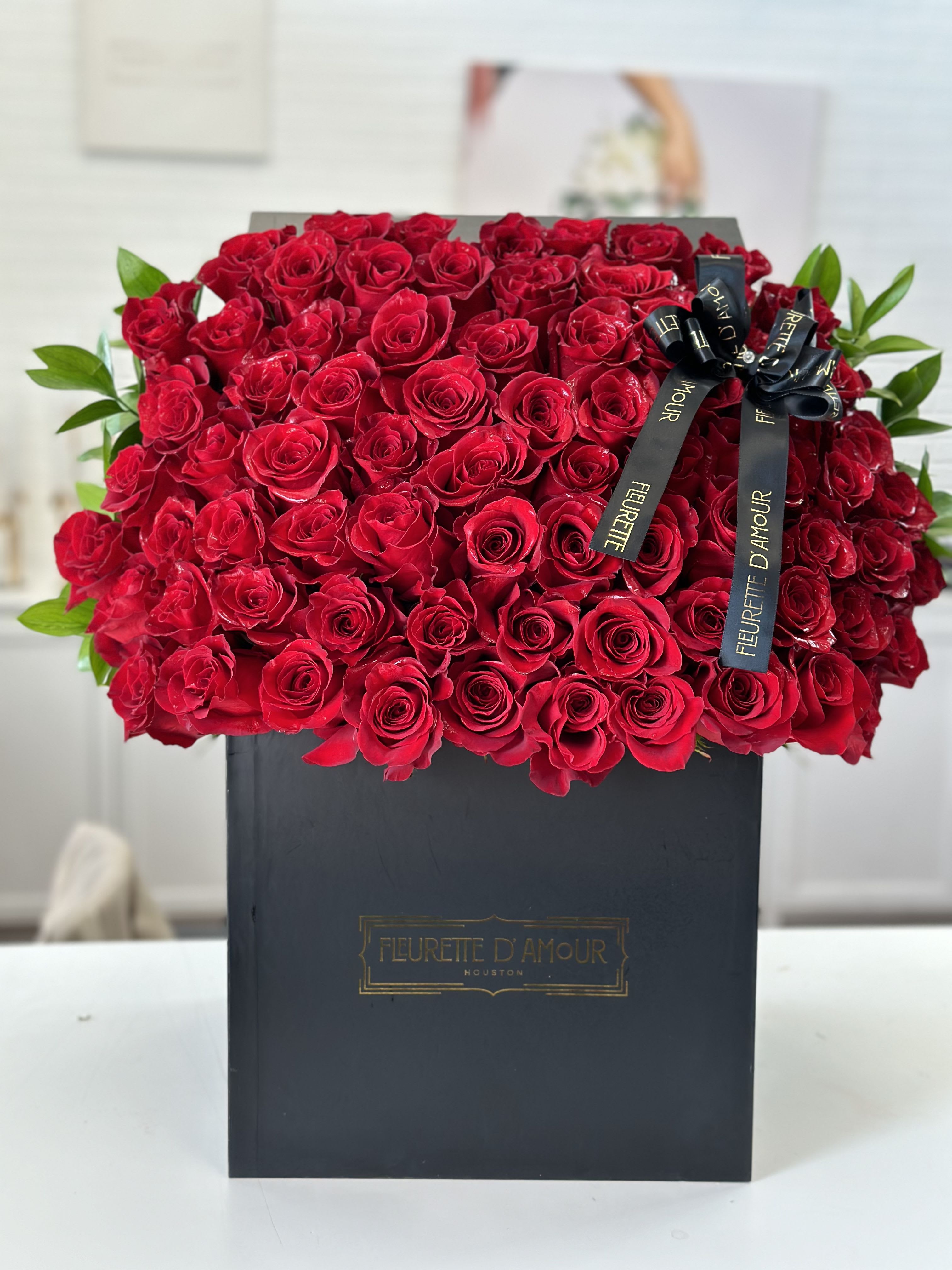 Large box of red roses with a black ribbon bow