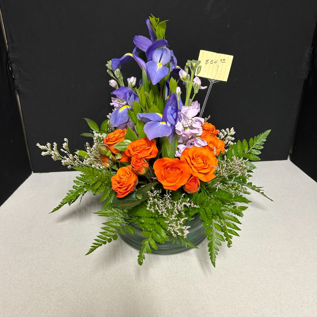 Orange roses and purple irises arranged in a low vase