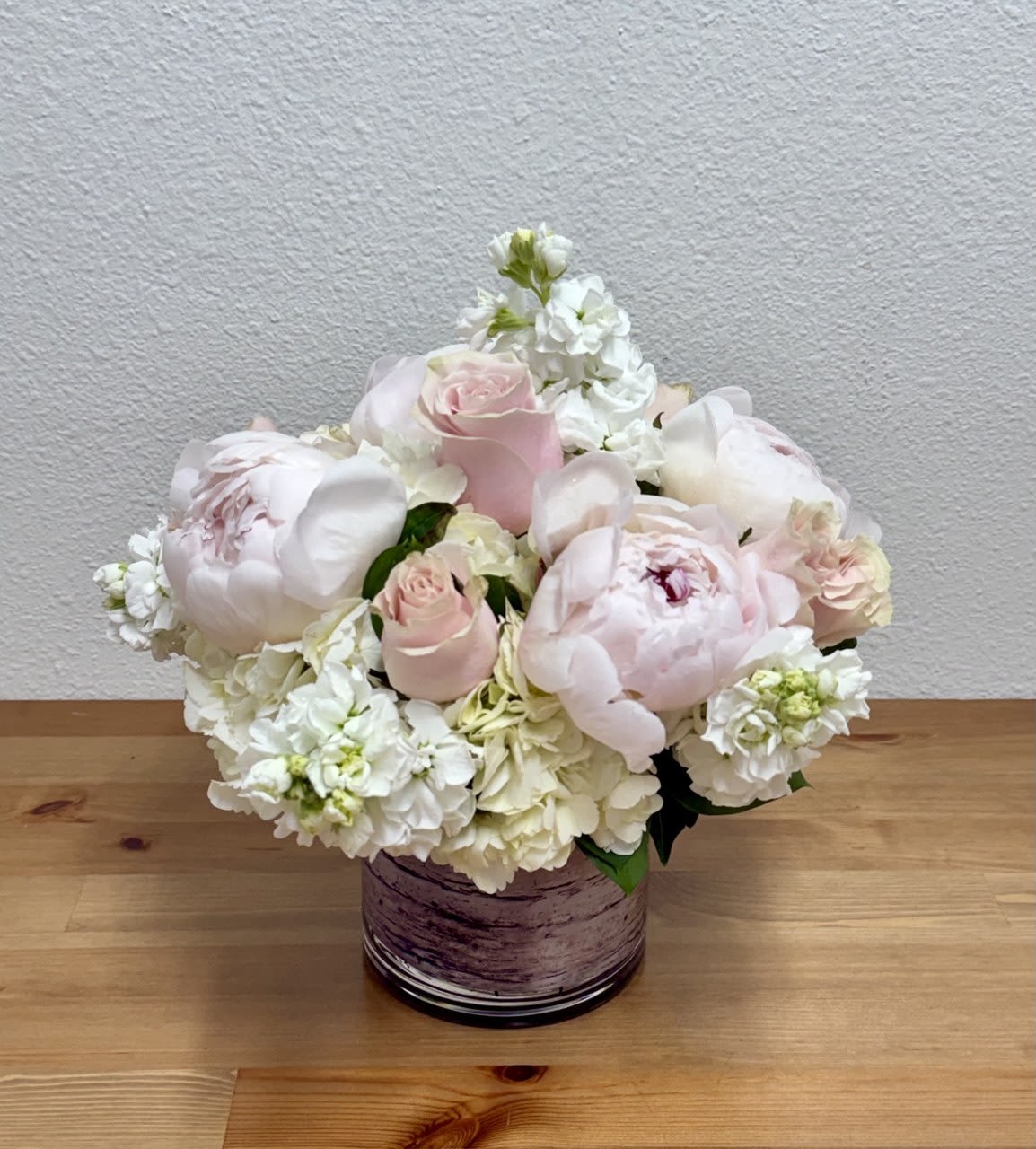 Blush pink roses and white peonies in a purple glass vase