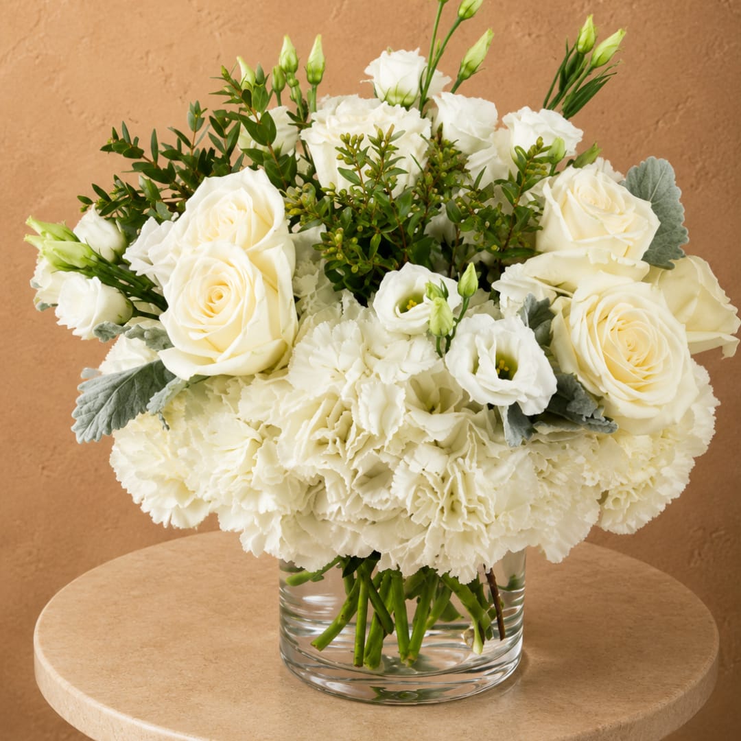White roses and carnations arranged in a clear glass vase