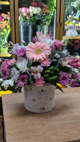 Pink and white mixed flower arrangement in a white ceramic container