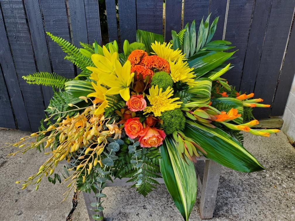 Bright tropical bouquet with yellow and orange flowers and lush greenery