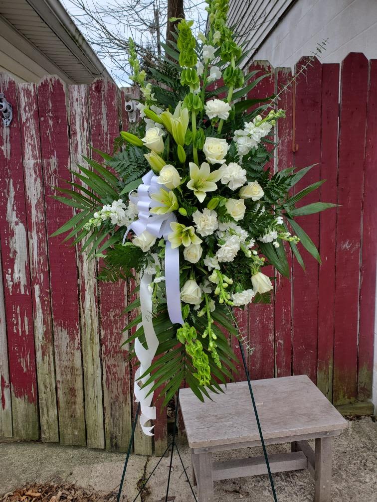 Tall white floral standing spray with ribbon on an easel