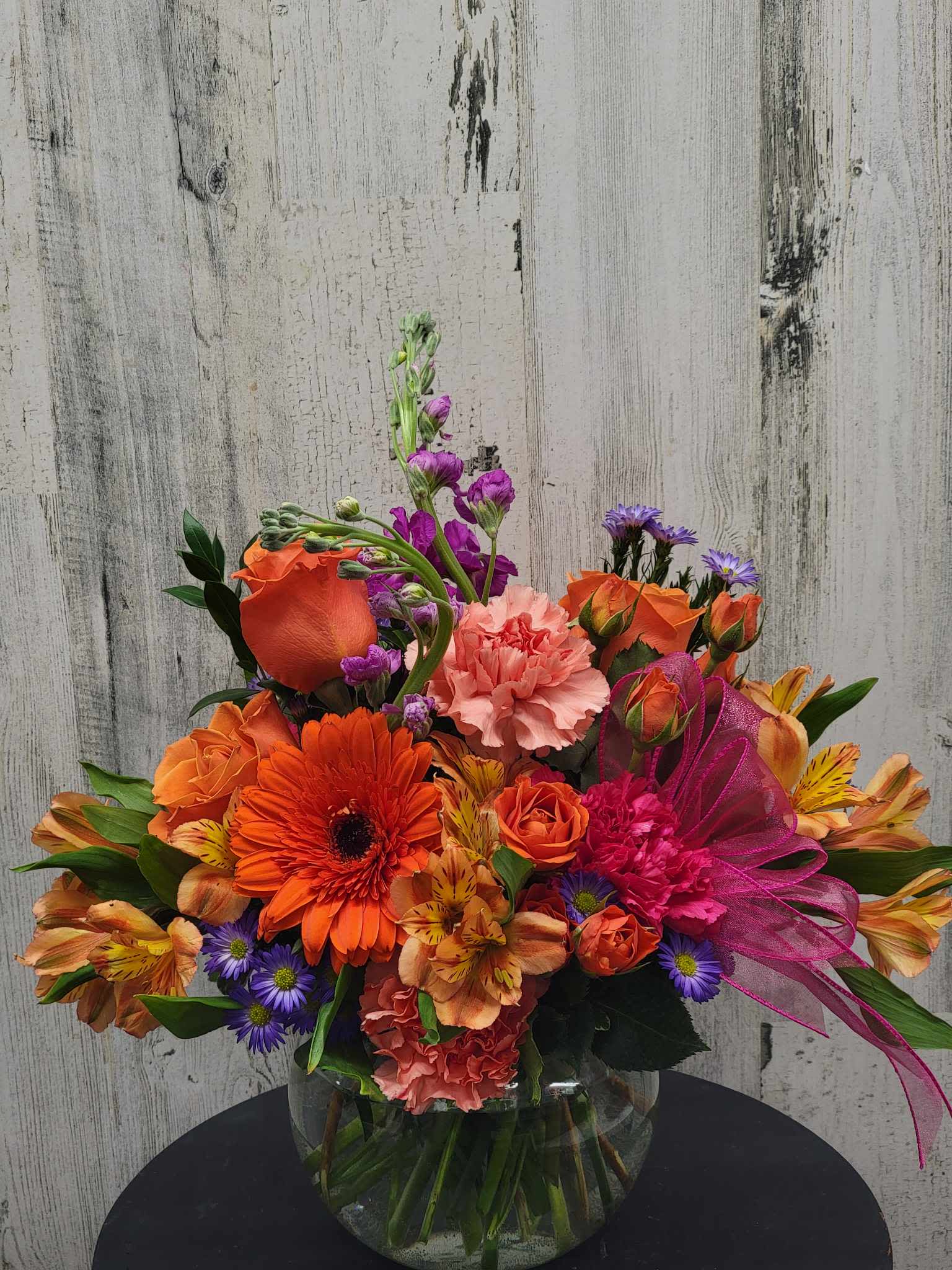 Bright mixed bouquet in a glass vase with orange, pink, and purple flowers