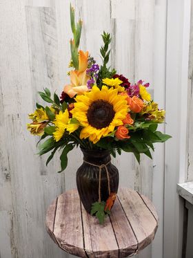 Sunflower and mixed flower arrangement in a dark vase