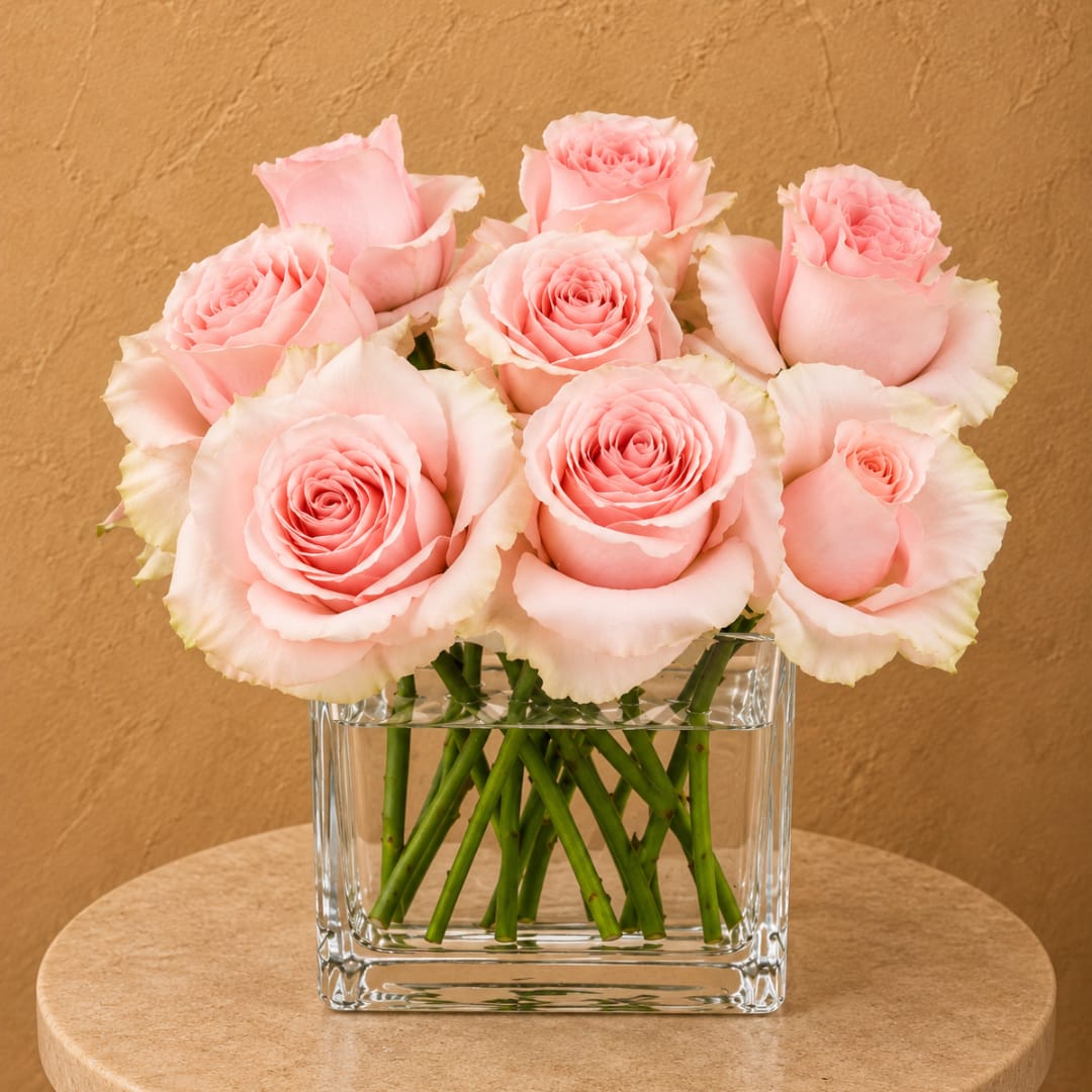Pink roses arranged in a clear square glass vase