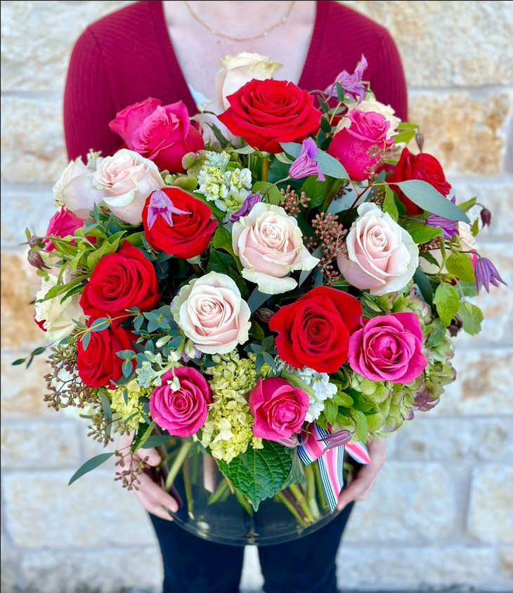 Large bouquet of red, pink, and white roses in a clear vase