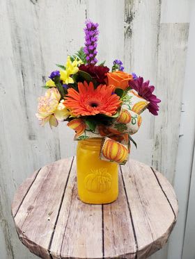 Colorful mixed flower arrangement in a yellow mason jar