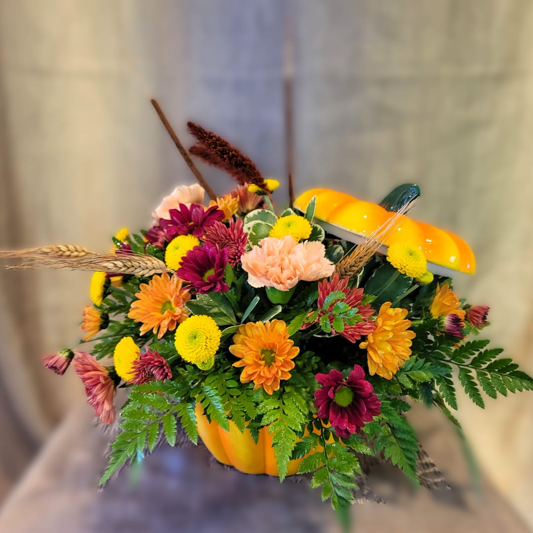 Mixed flower arrangement in a pumpkin-shaped container with autumn accents