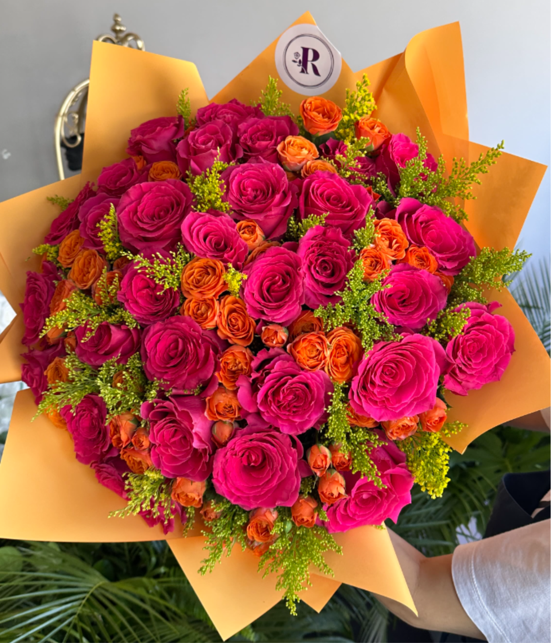 Autumn Radiance D - A radiant fall bouquet featuring fuchsia colored and orange roses, golden solidago, and lush seasonal greenery. Handcrafted by our West Hollywood florists, this elegant design captures the warmth of autumn. Perfect for Thanksgiving gifting and any occasion. Same-Day Delivery is usually available in white, red, peach, and pink. This bouquet comes without a vase. You can select a glass vase from the add-ons shown. SEASONAL or unavailable colors can be replaced with similar ones. DELUXE size is shown in the main picture.