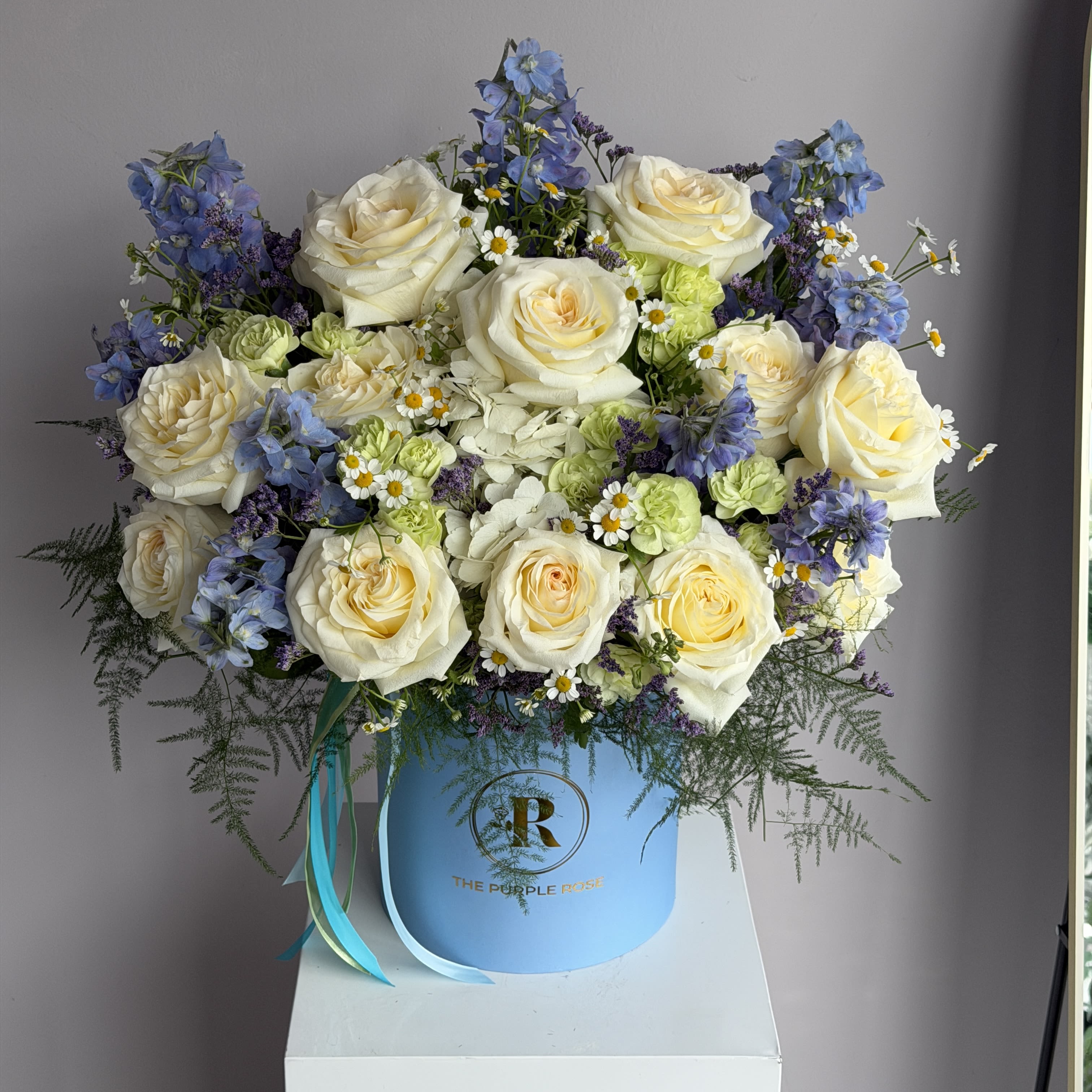 Sky Blue  - This vibrant flower arrangement combines cheerful Daisies, elegant Irises, romantic Roses, charming spray roses, and lush Hydrangeas, creating a lively display of color and texture.  The arrangement includes seasonal flowers. STANDARD size is shown in the main picture.