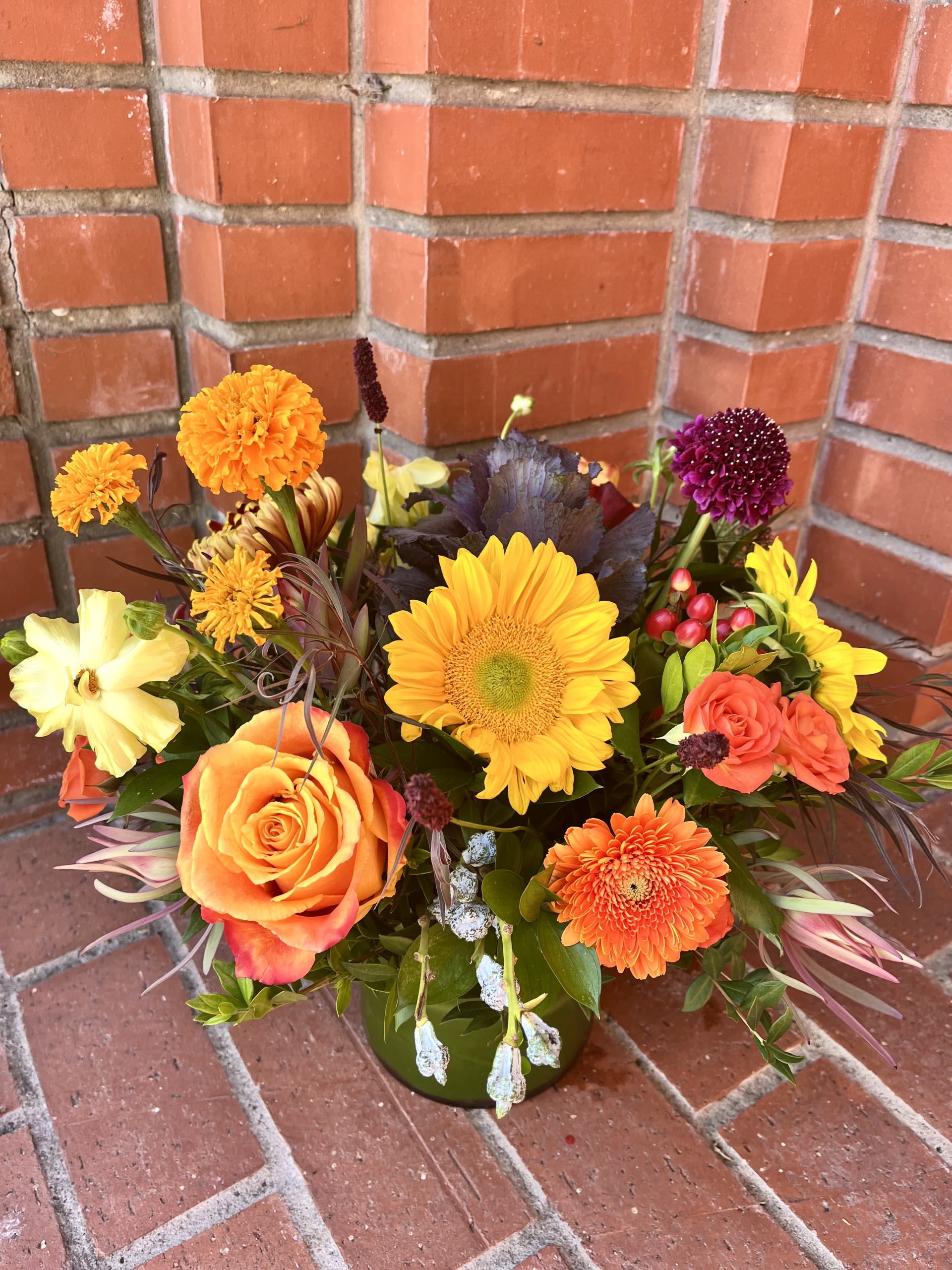 Mixed bouquet with sunflowers, roses, and chrysanthemums in a green vase
