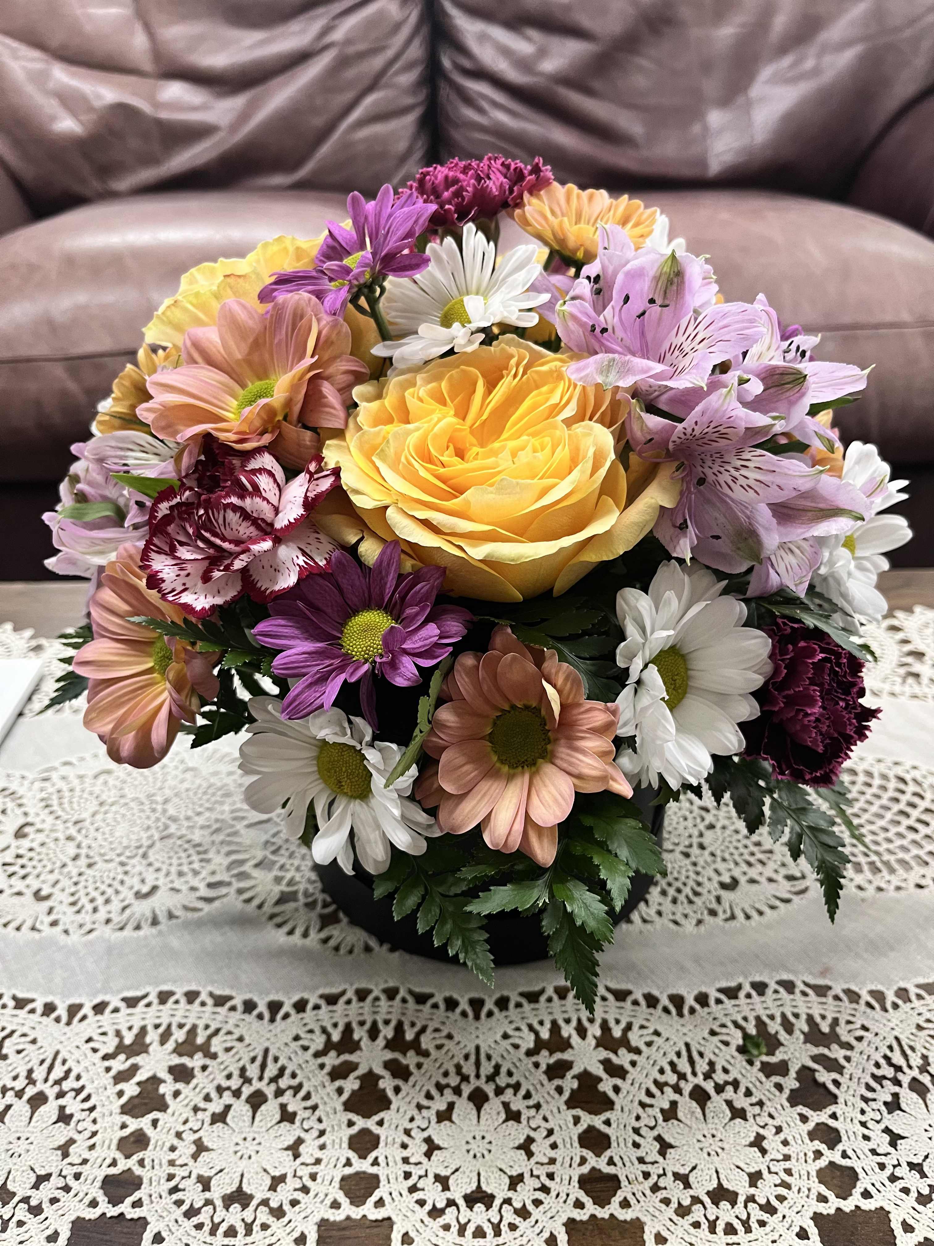 Soft Elegance  - Looking for something a little different than the traditional flowers in a vase? Soft elegance is a great option for you! With soft colors and a variety of long lasting flowers, this arrangement is sure to turn heads.  This arrangement features unique colored carnations, yellow turtle roses, three colors of daisies, and lavender alstroemeria in a black hat box. 