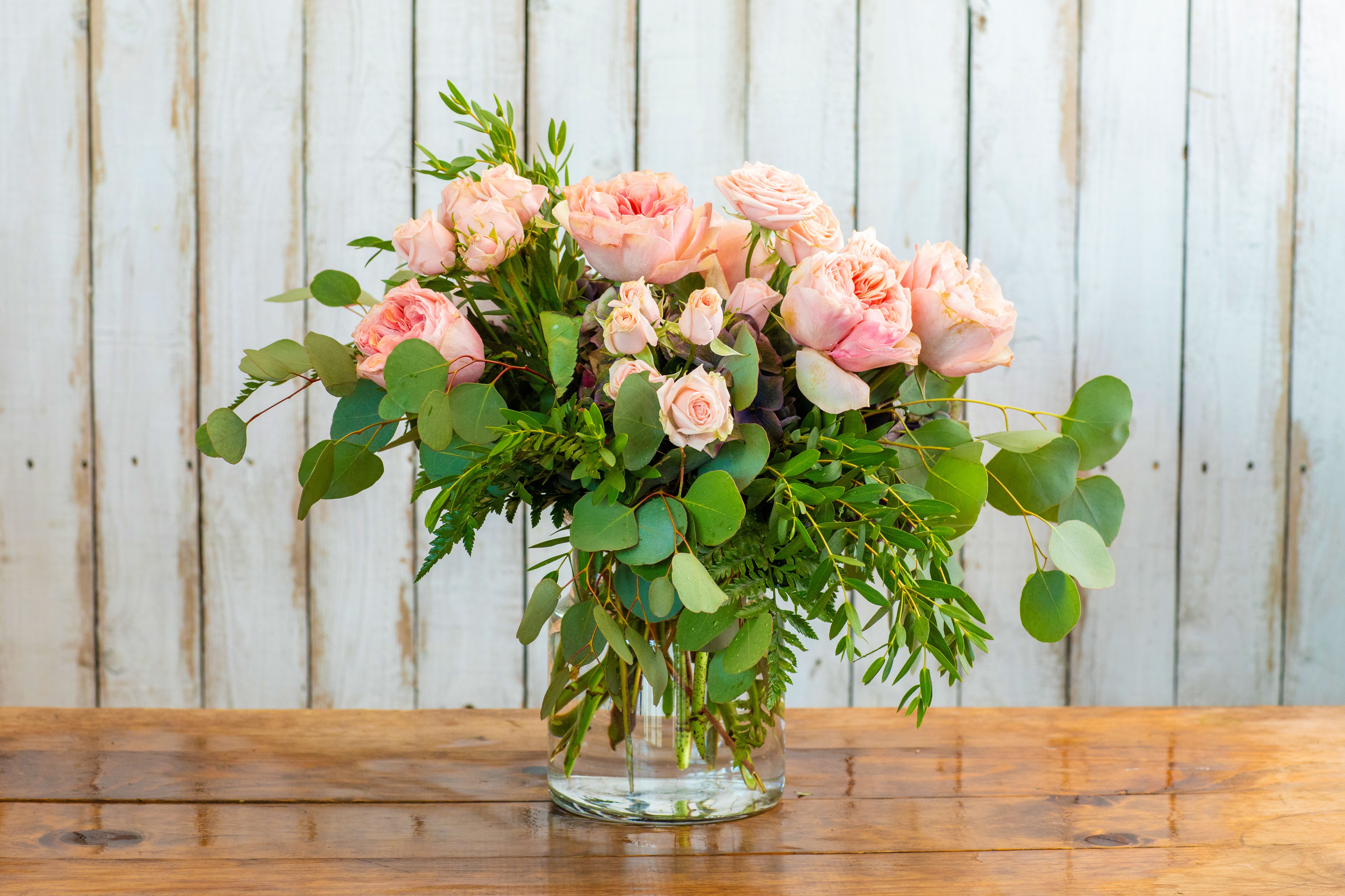 Pink roses in a clear glass vase with eucalyptus