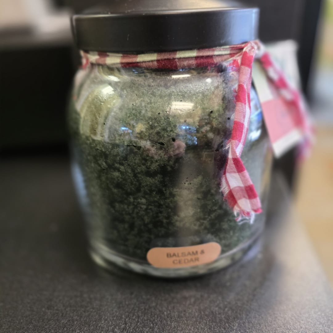 Glass jar candle with a black lid and plaid ribbon