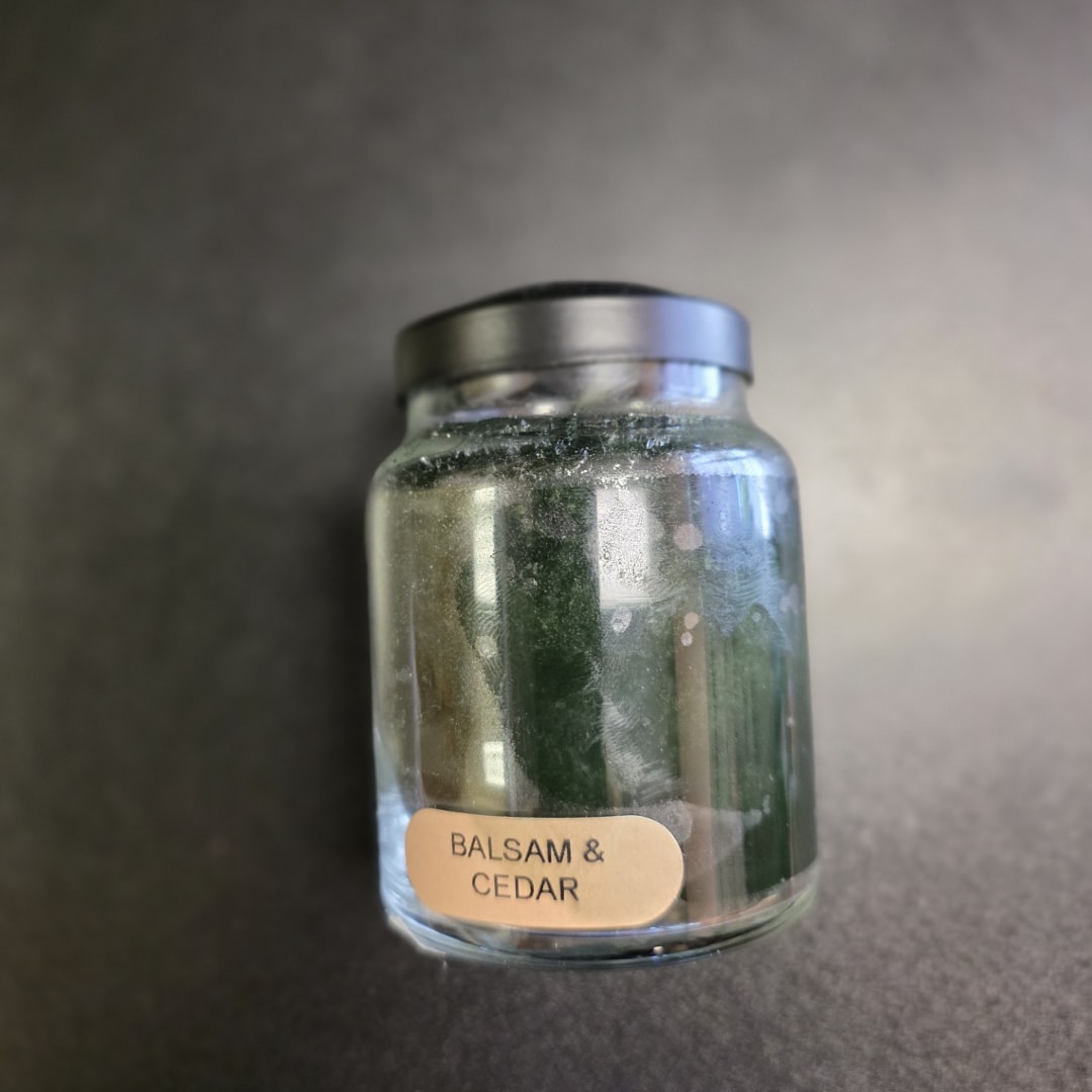 Glass jar candle labeled Balsam &amp; Cedar