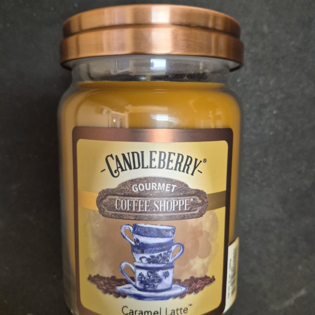 A caramel latte scented candle in a glass jar with a copper lid