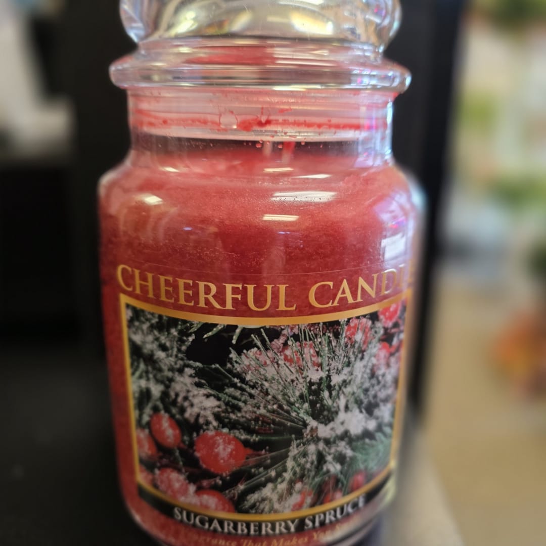 Red candle in a glass jar with a holiday-themed label