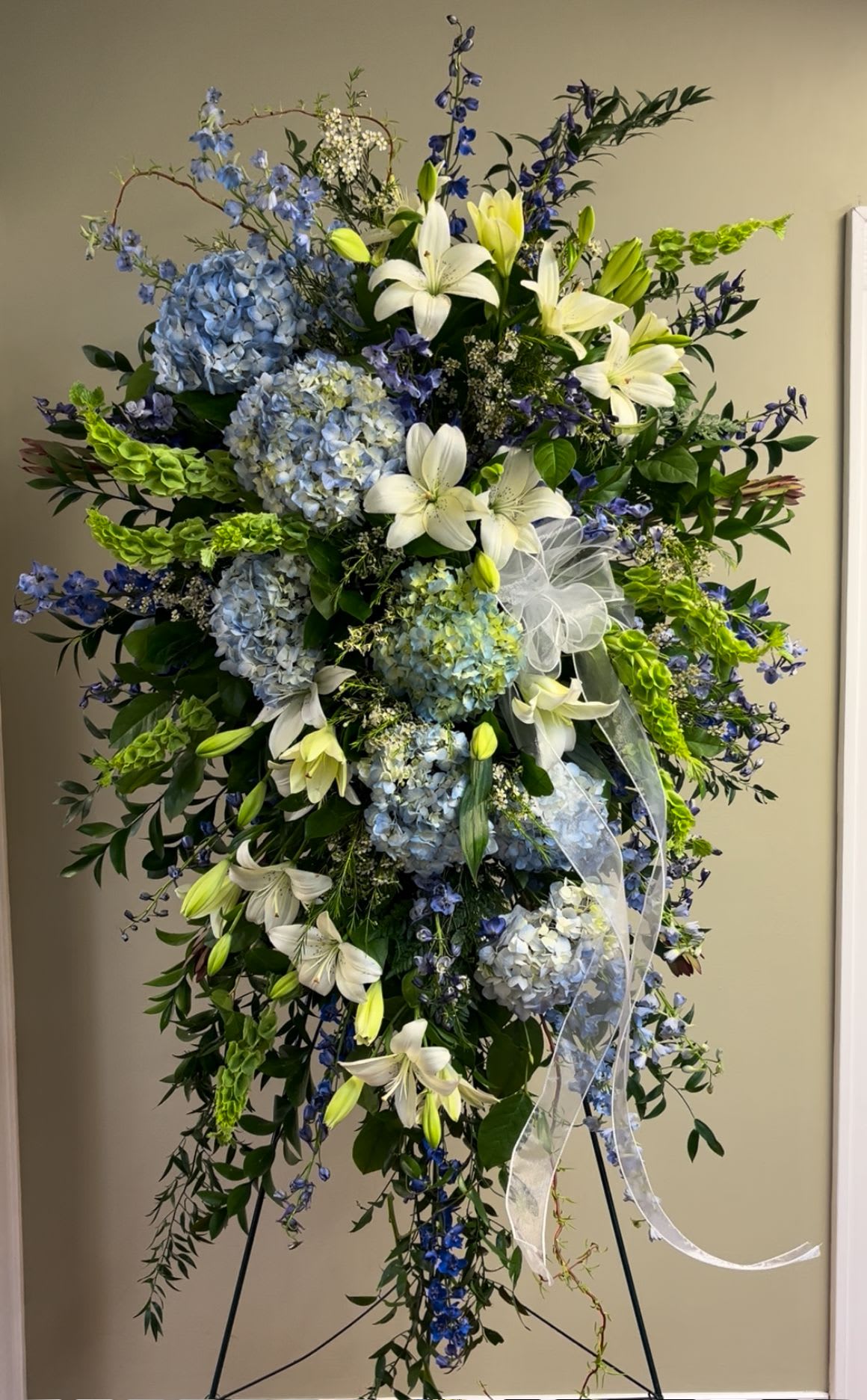 Tall standing floral spray with blue hydrangeas and white lilies