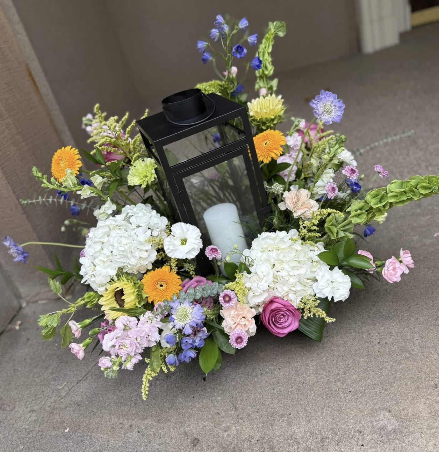 Floral wreath with a black lantern and white candle in the center