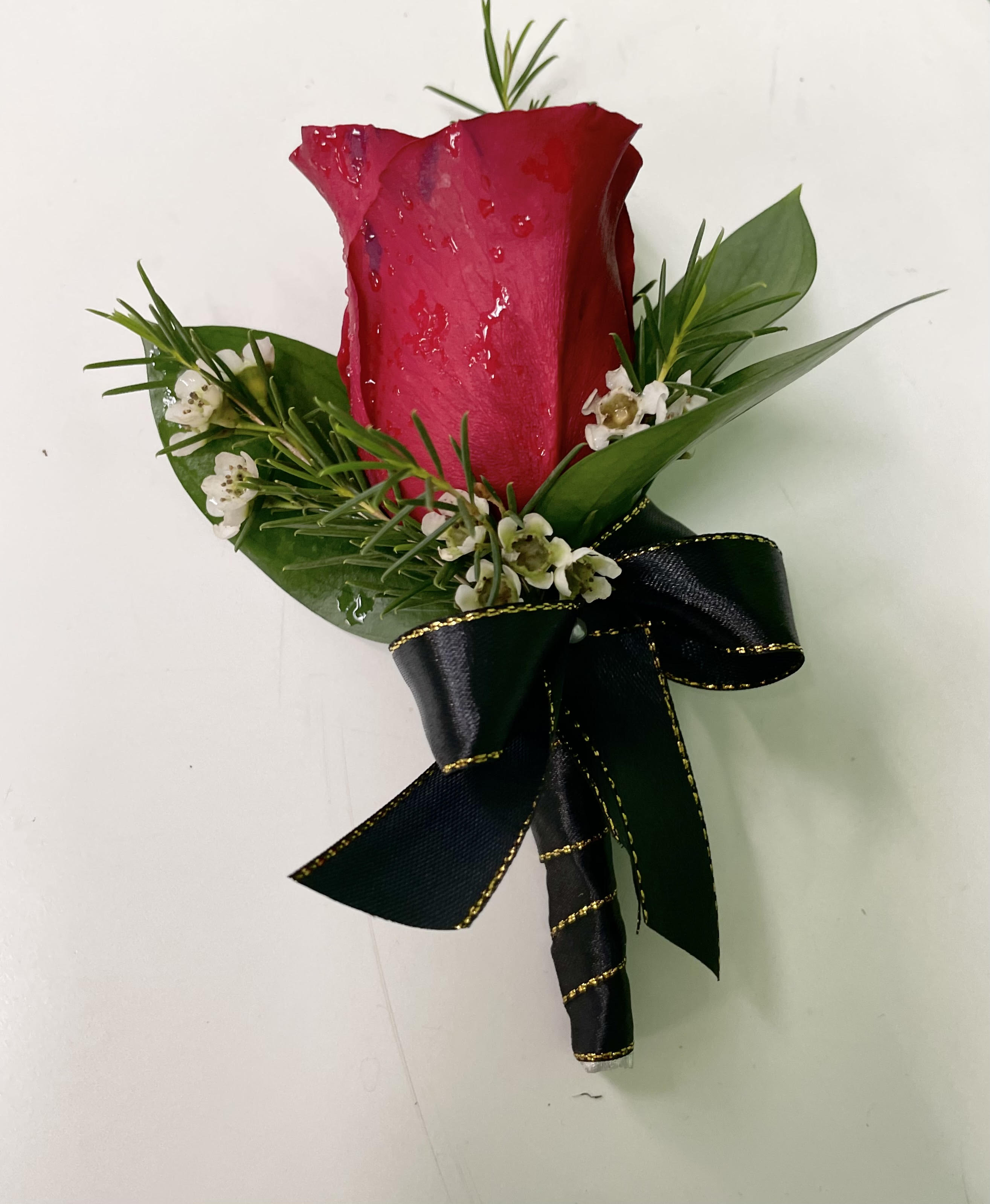 Single red rose boutonniere with small white flowers and a black ribbon