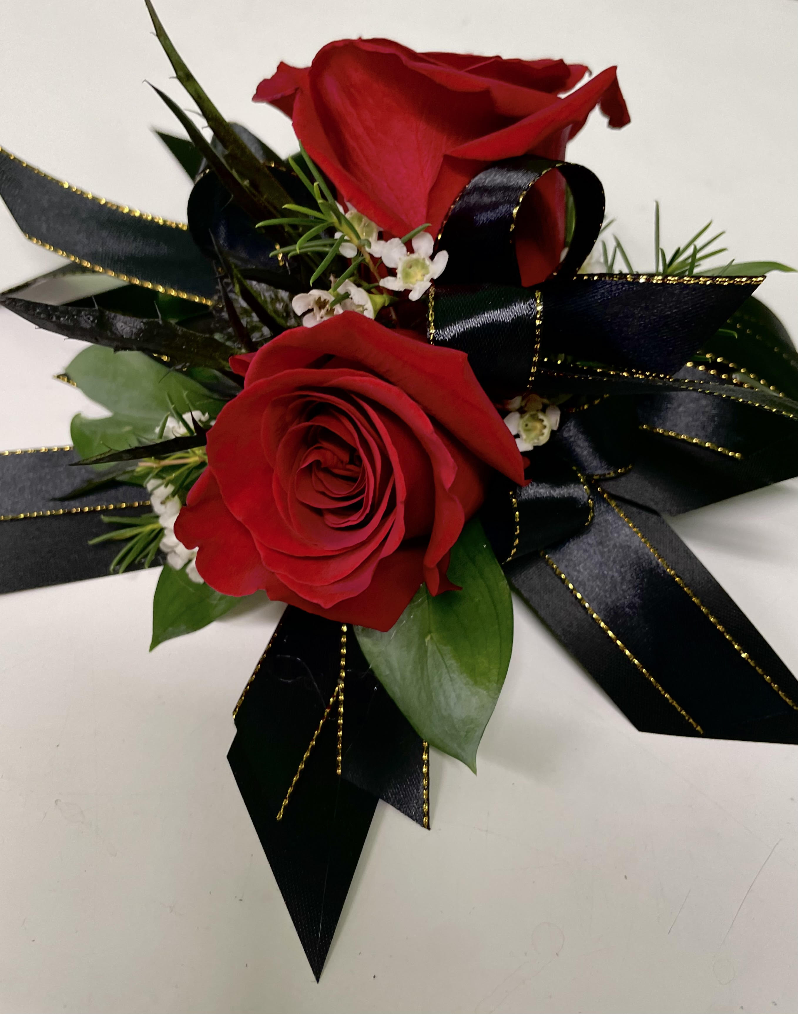 Two red roses with black ribbon accents and small white filler flowers