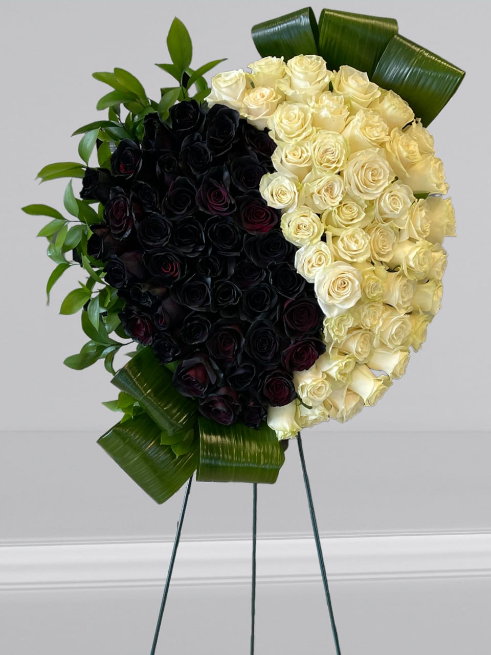 True Sympathy  - An all black and white tribute, this funeral heart shaped spray is pure and tranquil. Featuring a  black and white roses  and green palms this elegant funeral arrangement brings a feeling of peace to it's surroundings.