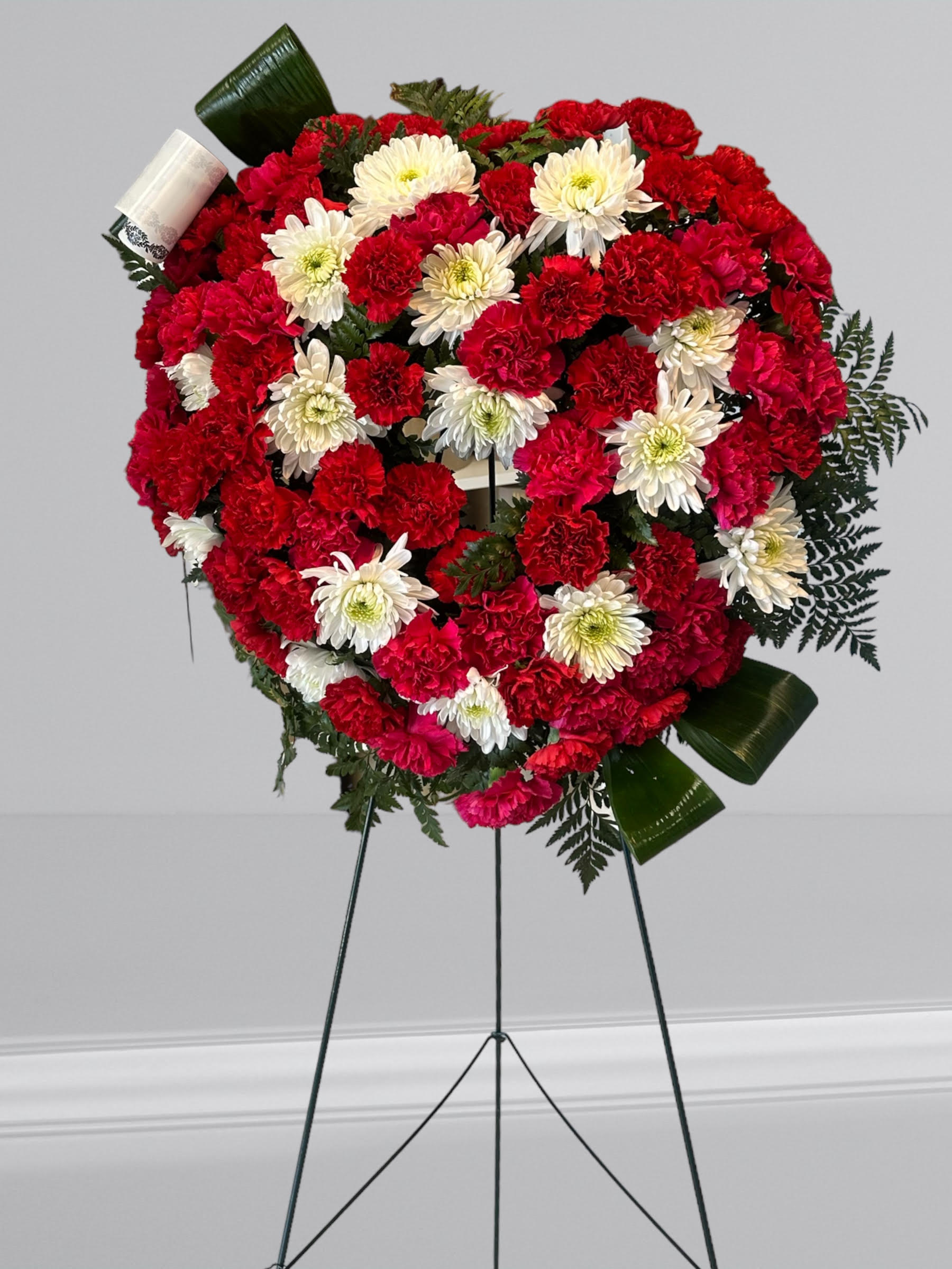 "Love in our Hearts" - An all white tribute, this heart shaped easel shows your everlasting love. Featuring a variety of white flowers and greenery, this heart with a trail of ivy compliments the beauty of life. 