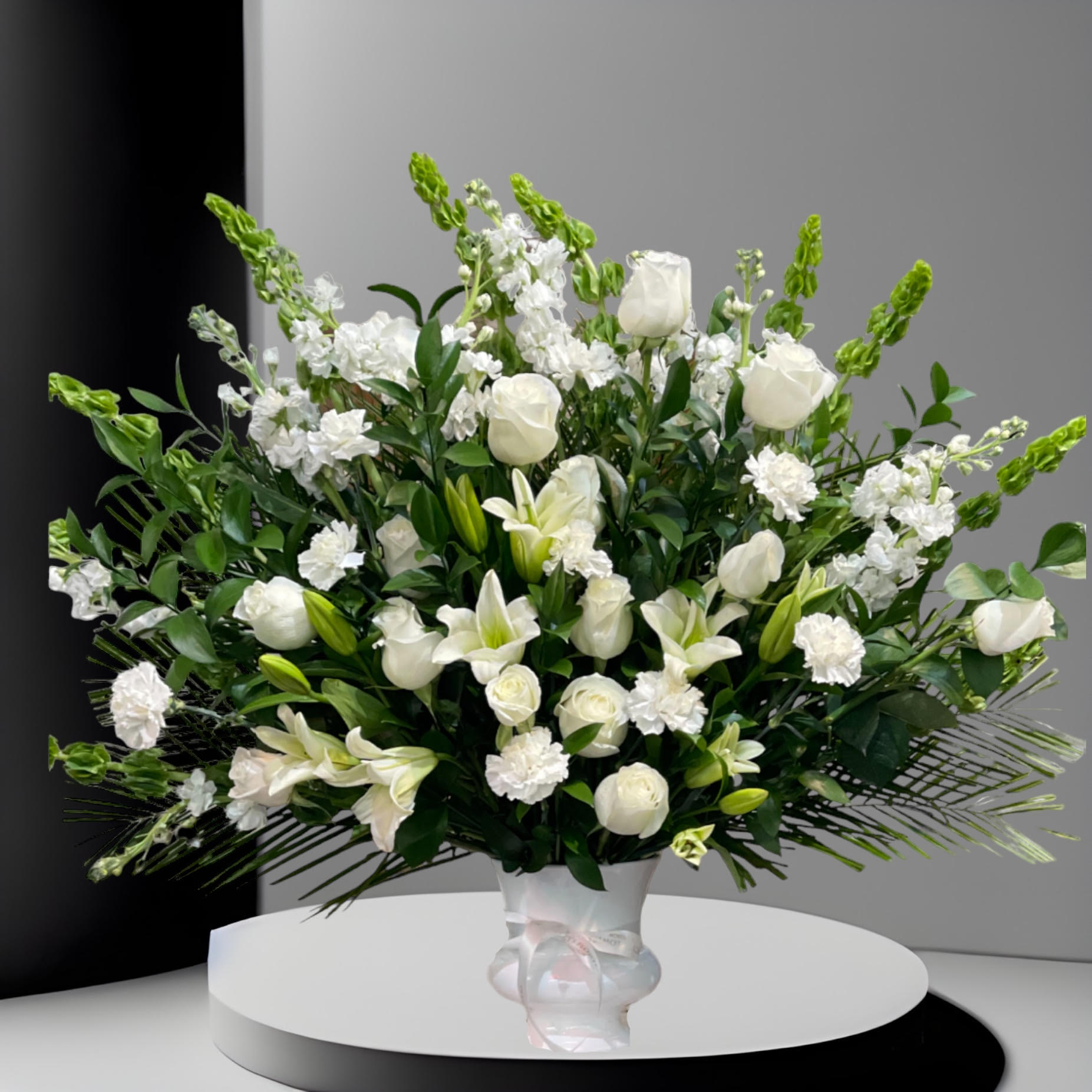 Sweet Comfort  - An all white tribute, this funeral basket is pure and tranquil. Featuring a variety of white flowers and greenery, this design reaches for the sky and evokes a feeling of peace upward and outward. 