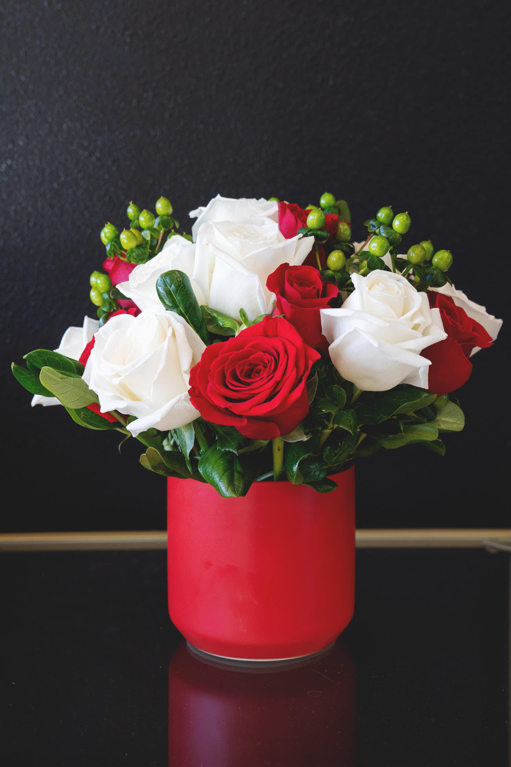 Red and white roses arranged in a red vase