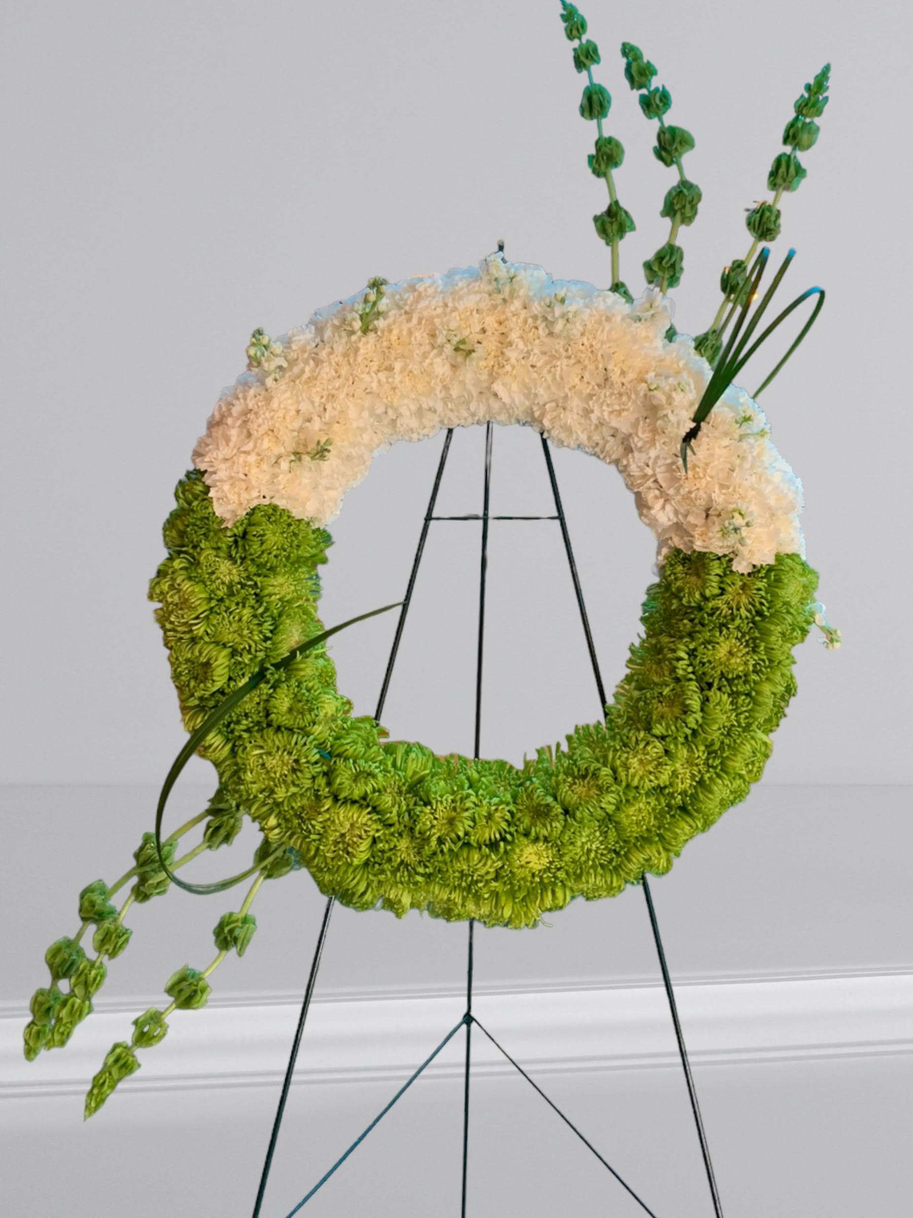 Warm Thoughts Wreath - A bright standing wreath of  fresh flowers in white carnations, green fuji spider mums, and bells of ireland will send a message of hope and harmony, and help to celebrate a meaningful life.