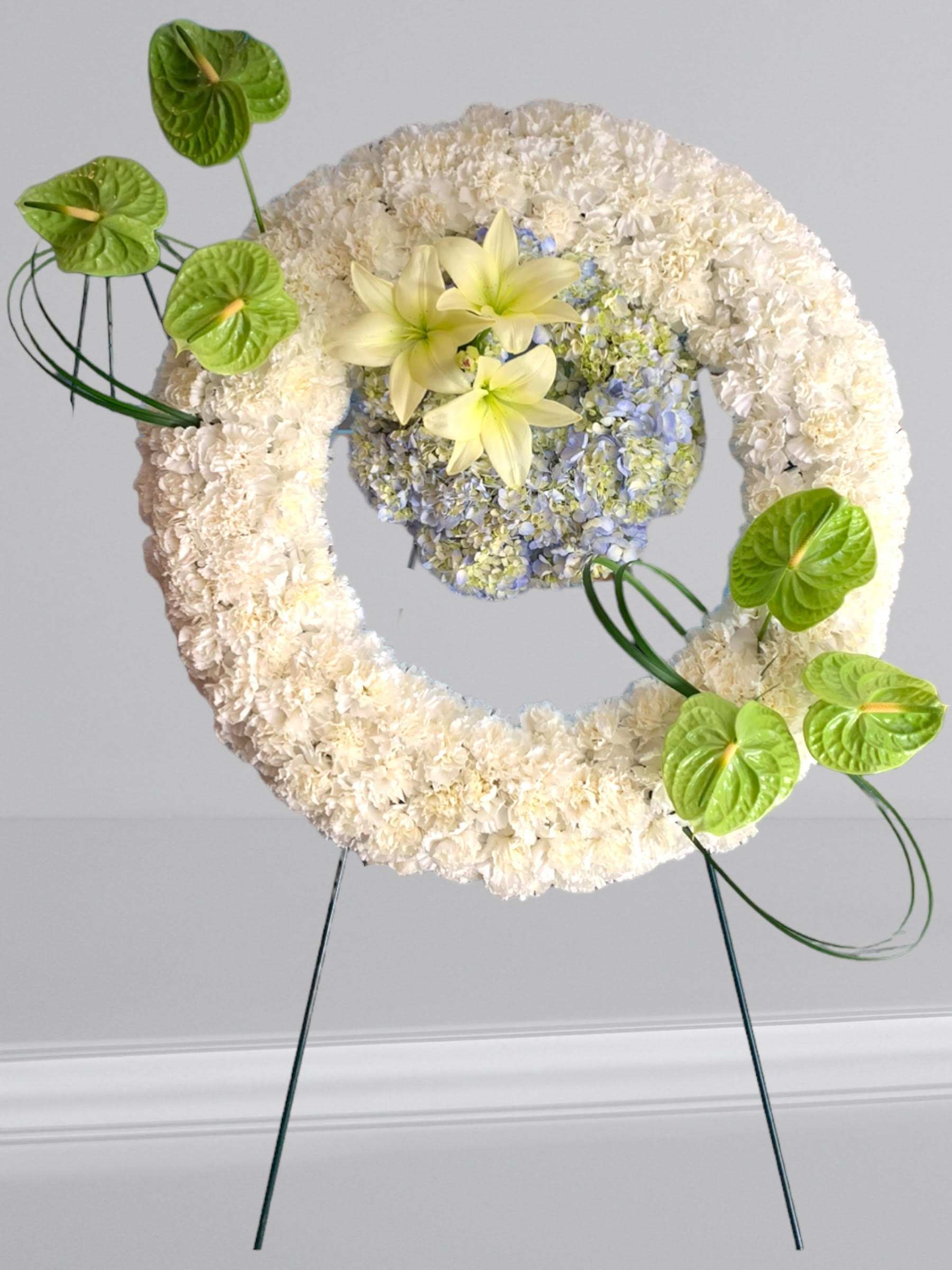 Spirit of Hope Standing Spray - Share the spirit of hope and faith with a generous standing spray of white, and green blossoms – including lilies, hydrangeas and carnations and  green anthuriums.   A lovely way to express your sympathies.