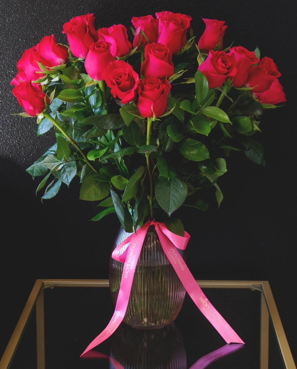 Bouquet of red roses in a ribbed glass vase with a pink ribbon